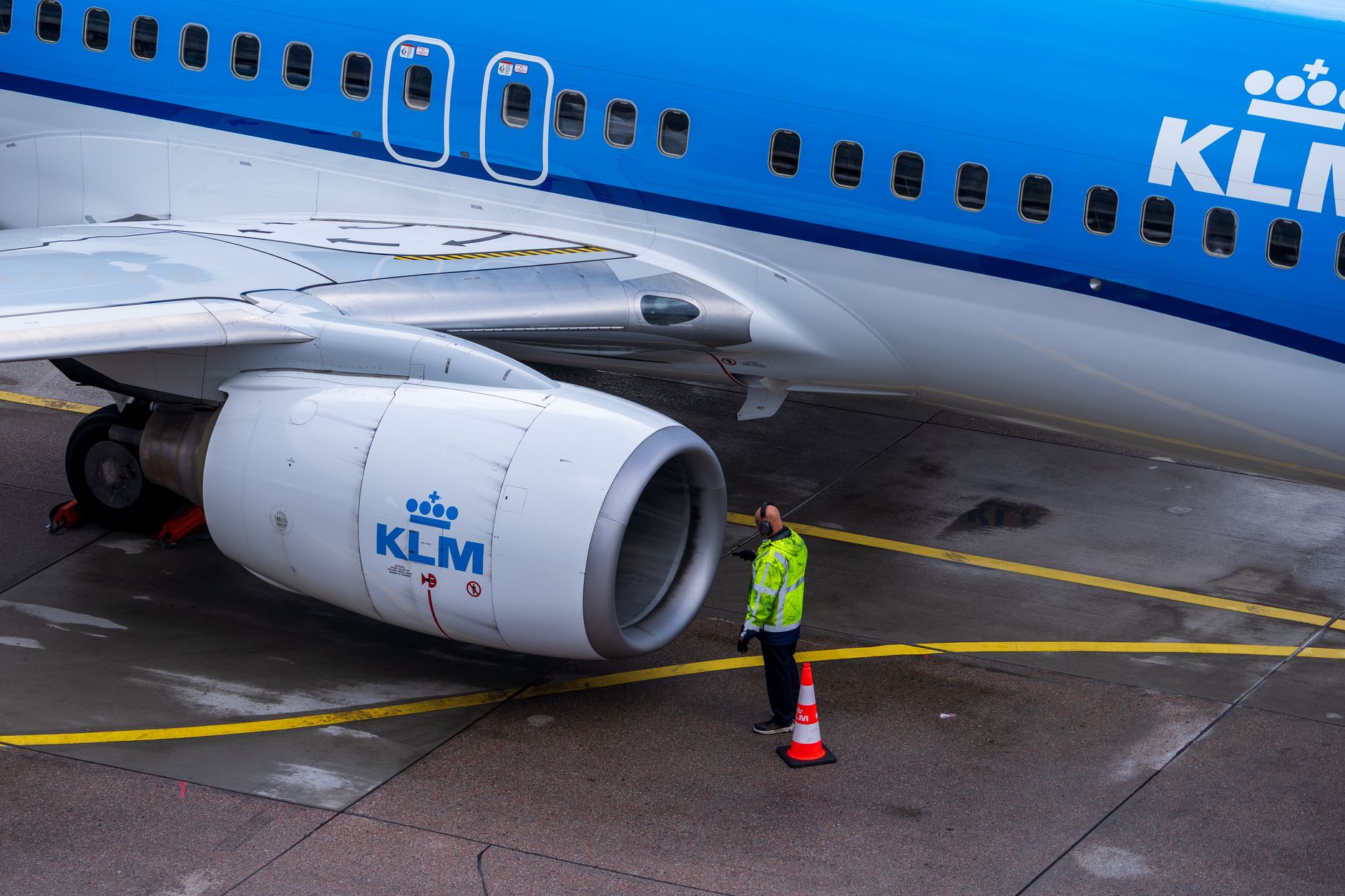 Een KLM-vliegtuig ondergaat onderhoud op het platform, terwijl een technicus het inspecteert.