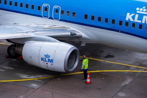Free A KLM aircraft undergoing maintenance on the tarmac with an engineer inspecting it. Stock Photo