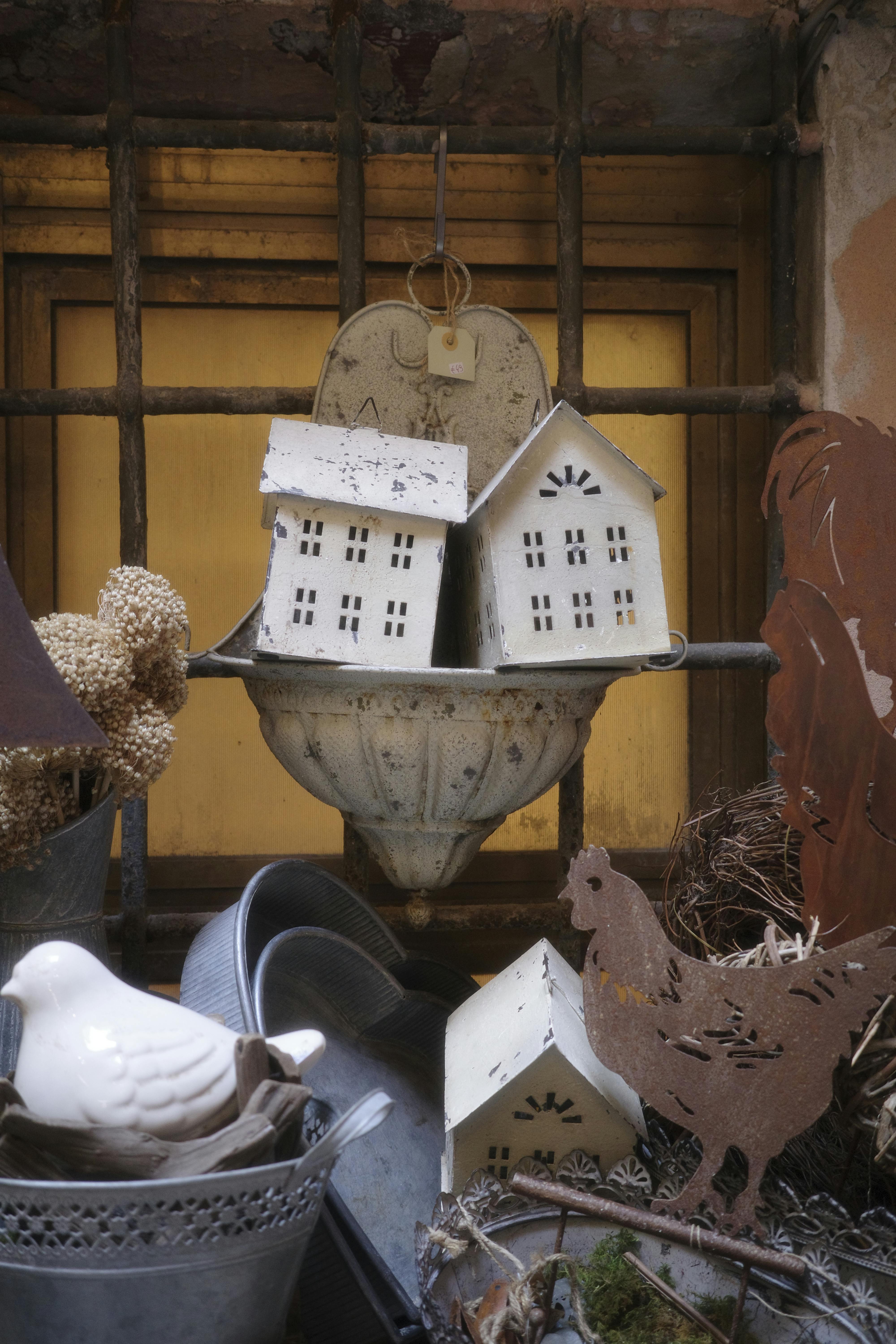 grátis Uma encantadora exposição de casinhas de pássaros de metal e elementos decorativos rústicos em um ambiente vintage. Foto profissional