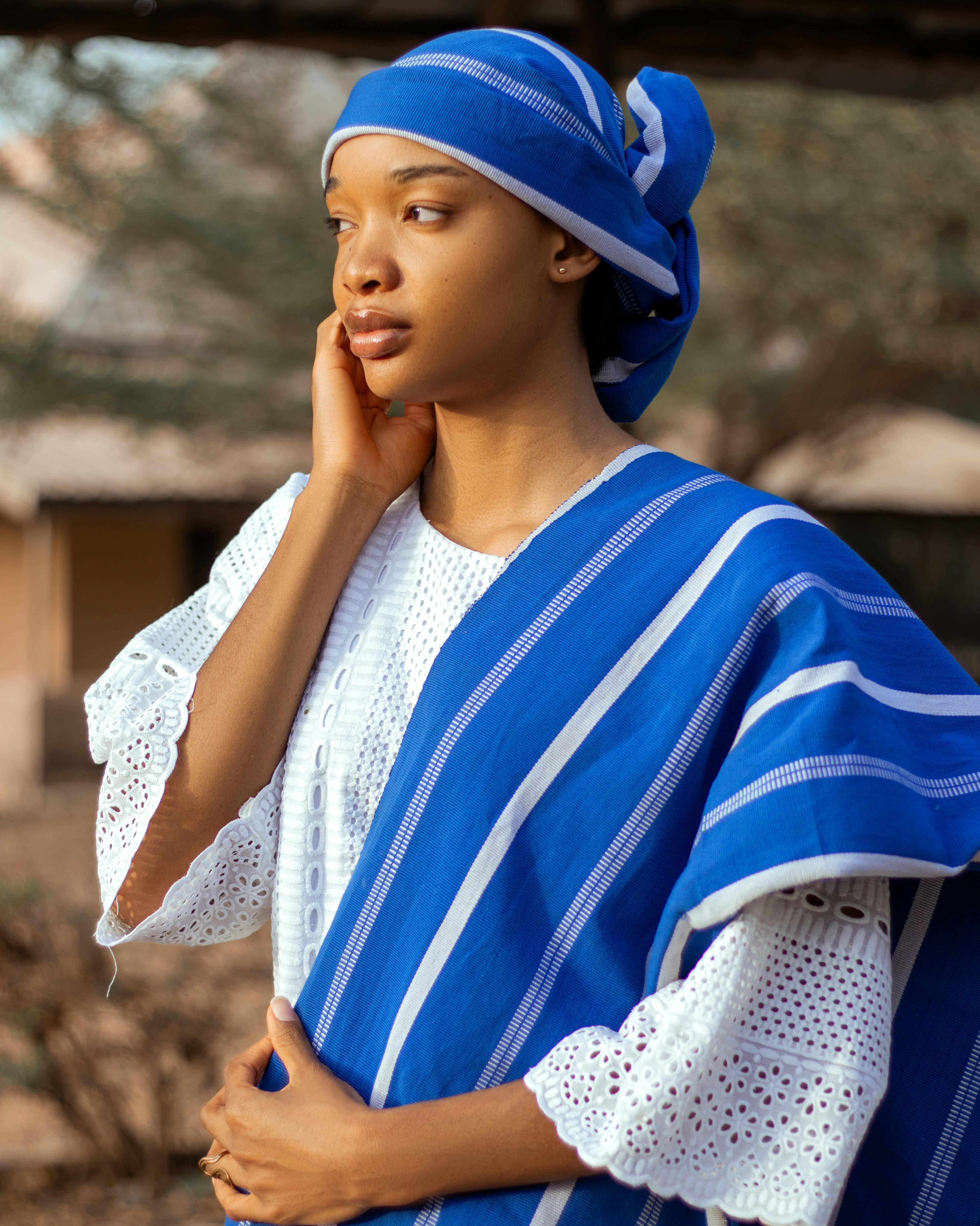 grátis Retrato de uma jovem mulher vestindo roupas tradicionais azuis com padrões intrincados ao ar livre. Foto profissional