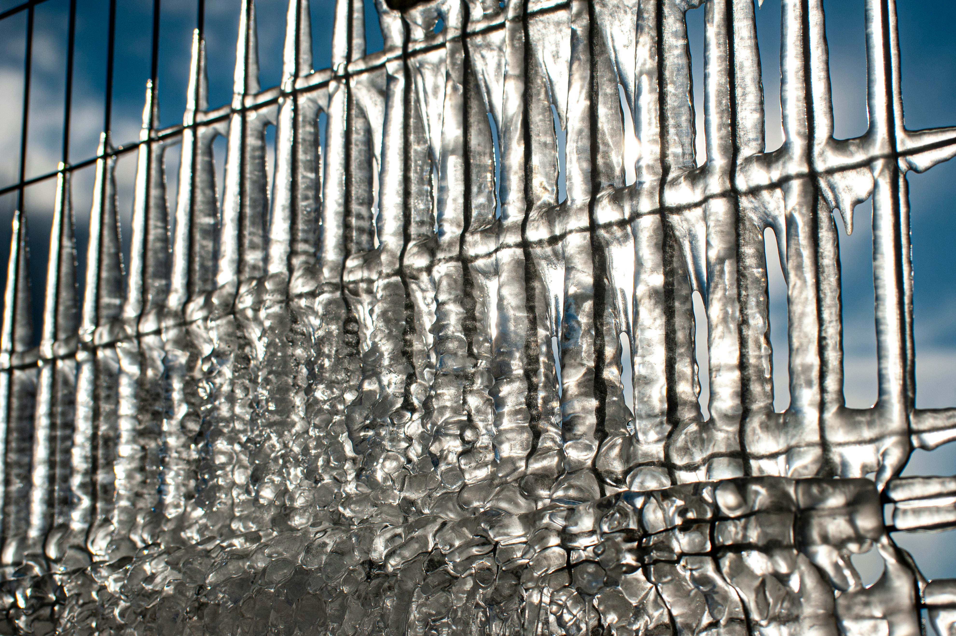 ฟรี ภาพระยะใกล้ของแท่งน้ำแข็งที่ก่อตัวบนรั้วโลหะ ส่องประกายระยิบระยับในแสงแดดฤดูหนาว ที่เมืองทบิลิซี ประเทศจอร์เจีย คลังภาพถ่าย