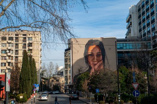 Striking mural depicting a woman's face adorns a building in Tbilisi, Georgia, blending art and city life.