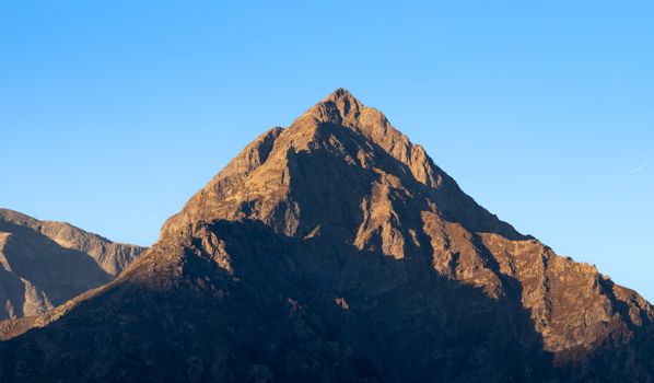 Beautiful alpine mountain peak bathed in warm sunrise light, capturing nature's serenity and grandeur.
