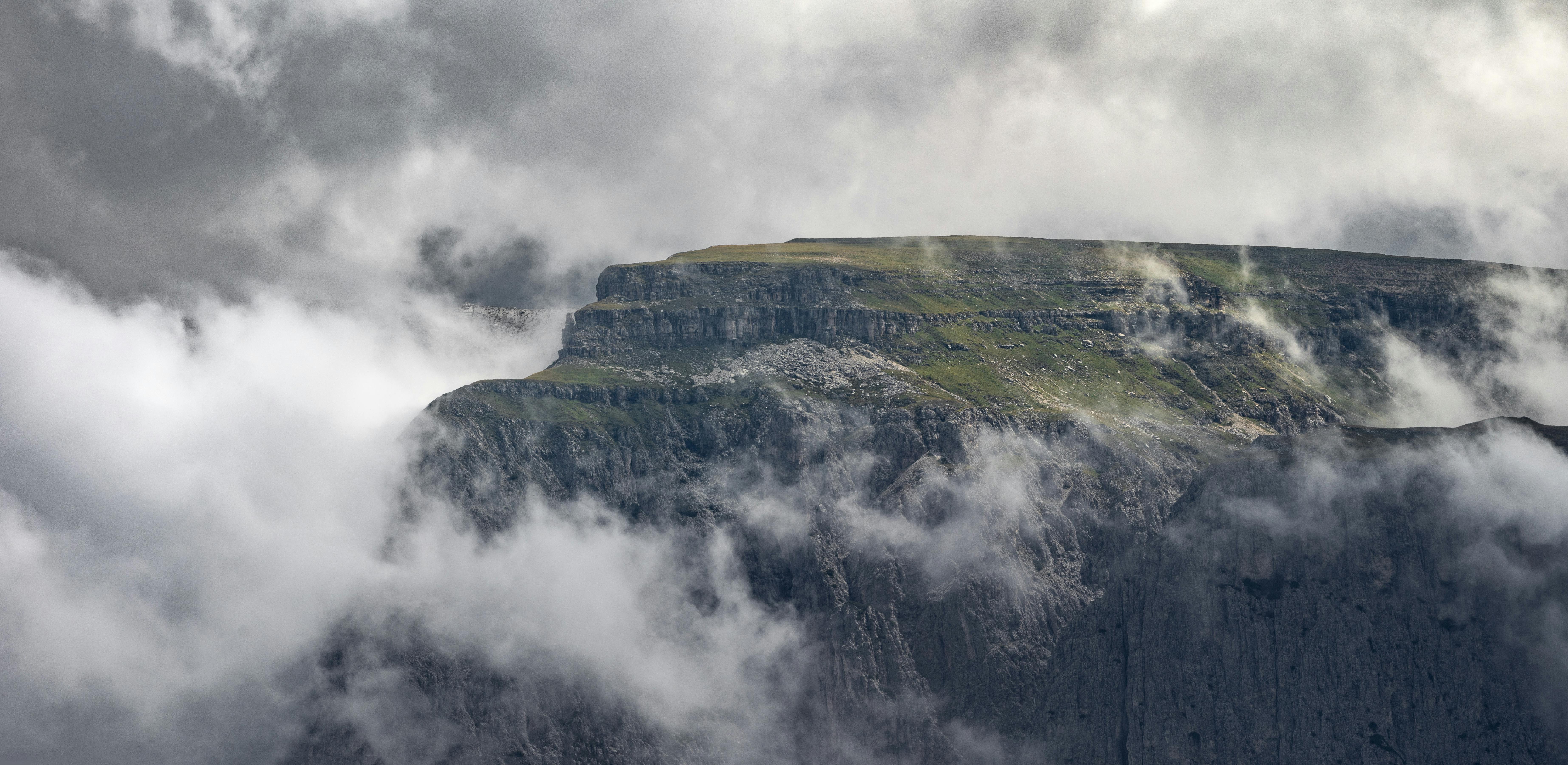 무료 구름으로 뒤덮인 산봉우리와 그 위로 펼쳐진 드라마틱한 하늘의 매혹적인 풍경. 스톡 사진