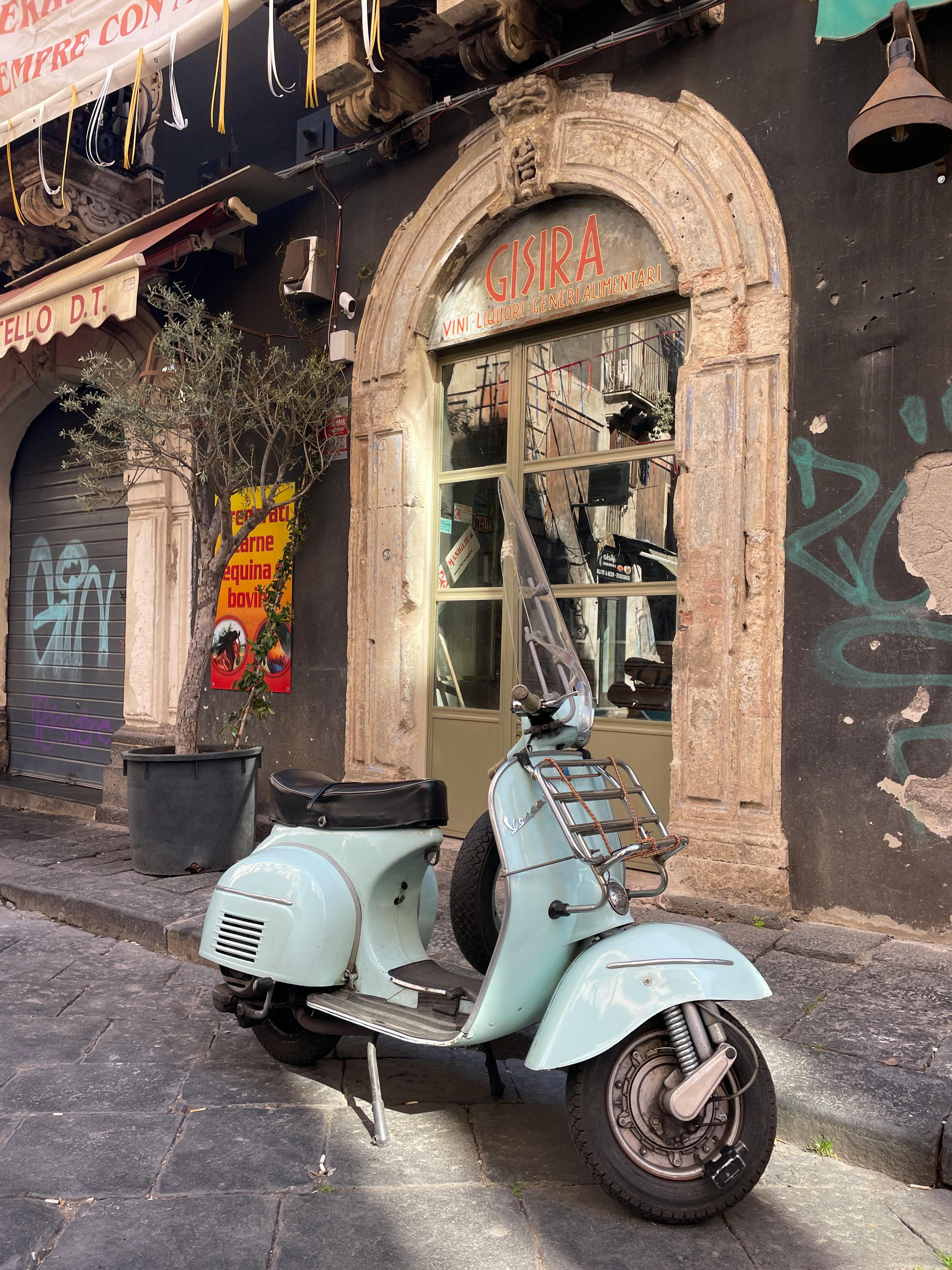 免费 一辆经典的 Vespa 踏板车停在意大利巴勒莫迷人街道上一栋古朴的建筑外。 素材图片