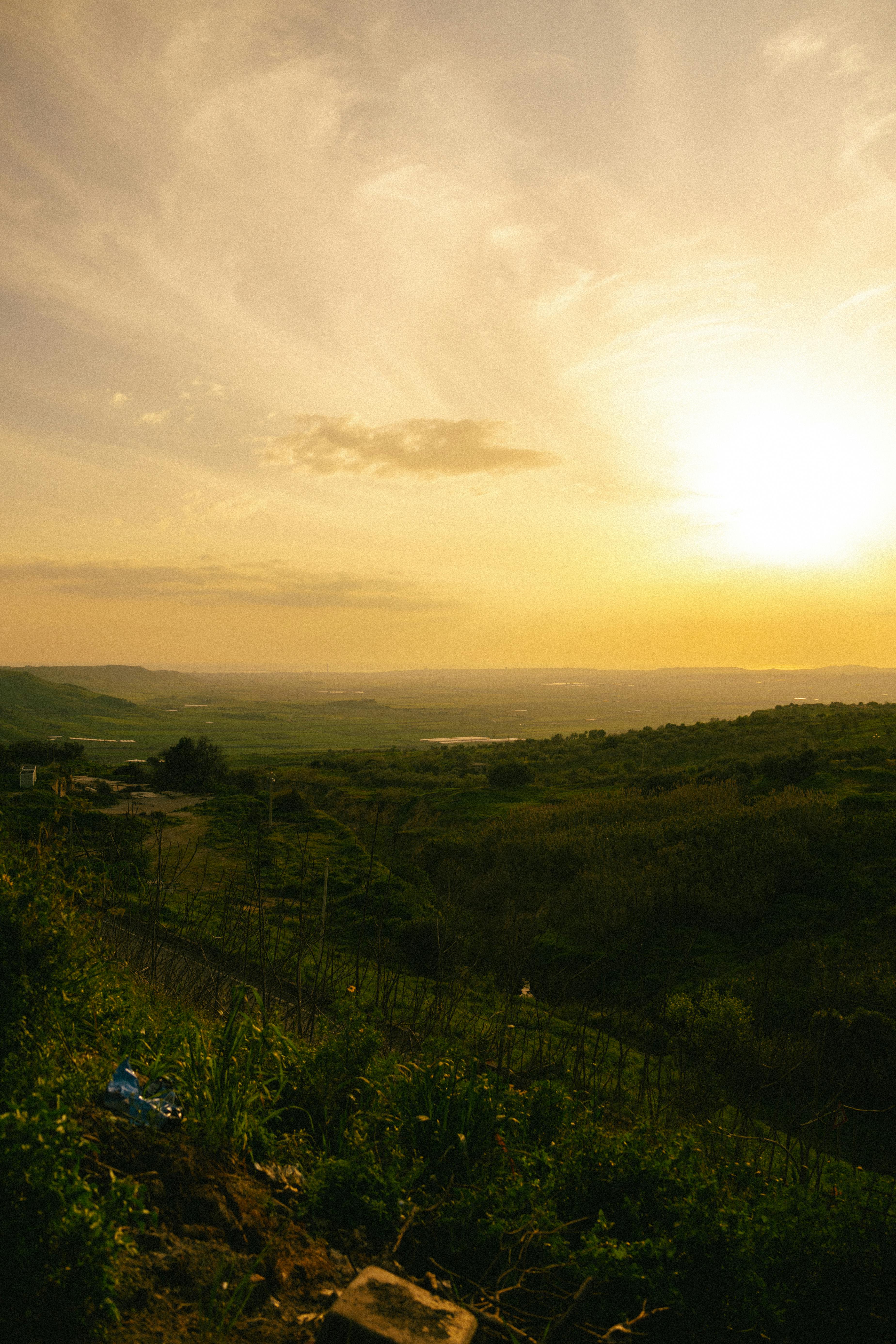 gratis Prachtige zonsondergang boven de glooiende heuvels van Niscemi, Sicilië, met weelderig groen en een levendige hemel. Stockfoto