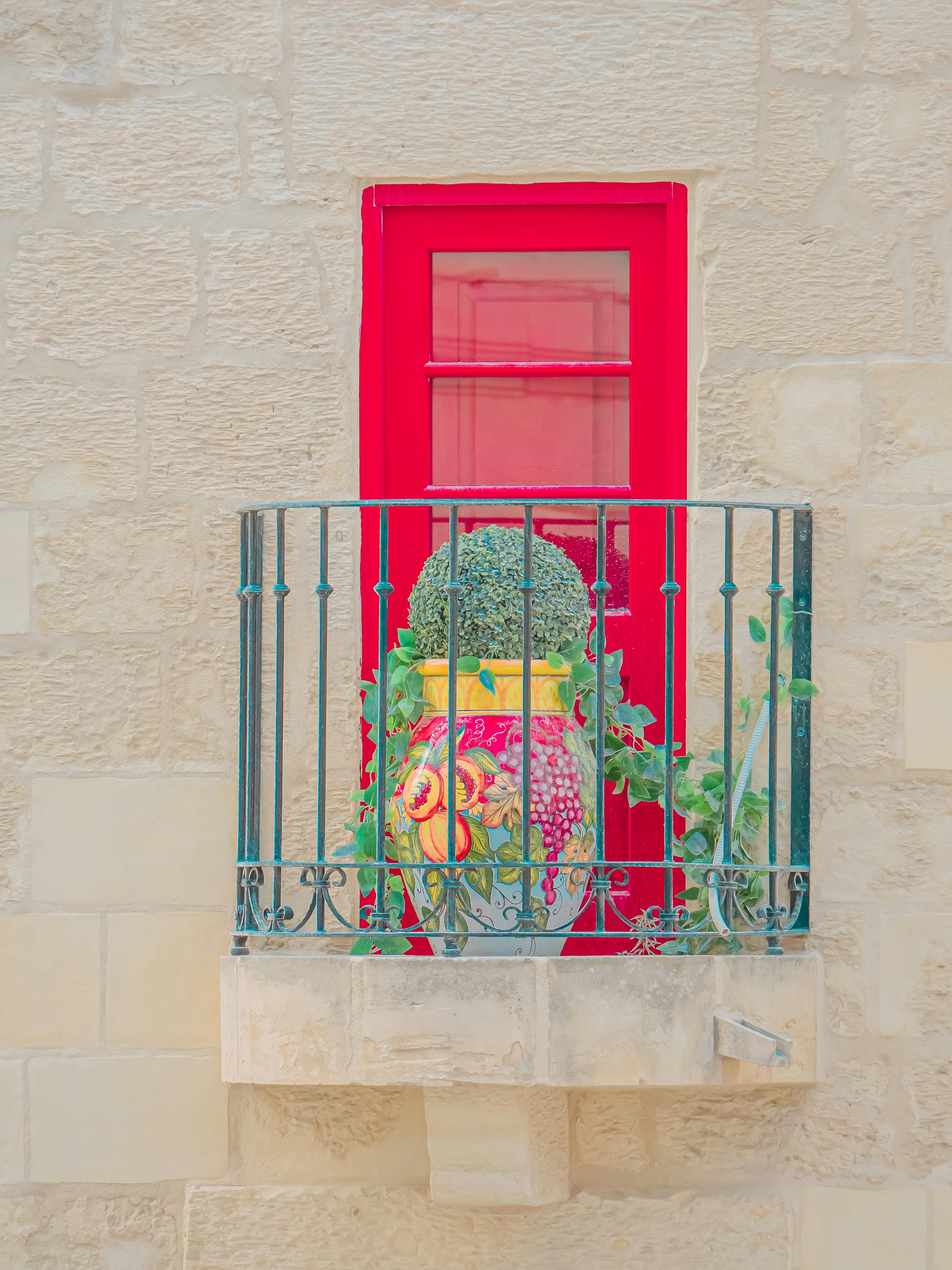 Gratuit Porte rouge vif avec balcon décoratif et plante en pot sur la façade en pierre d'un immeuble. Photos