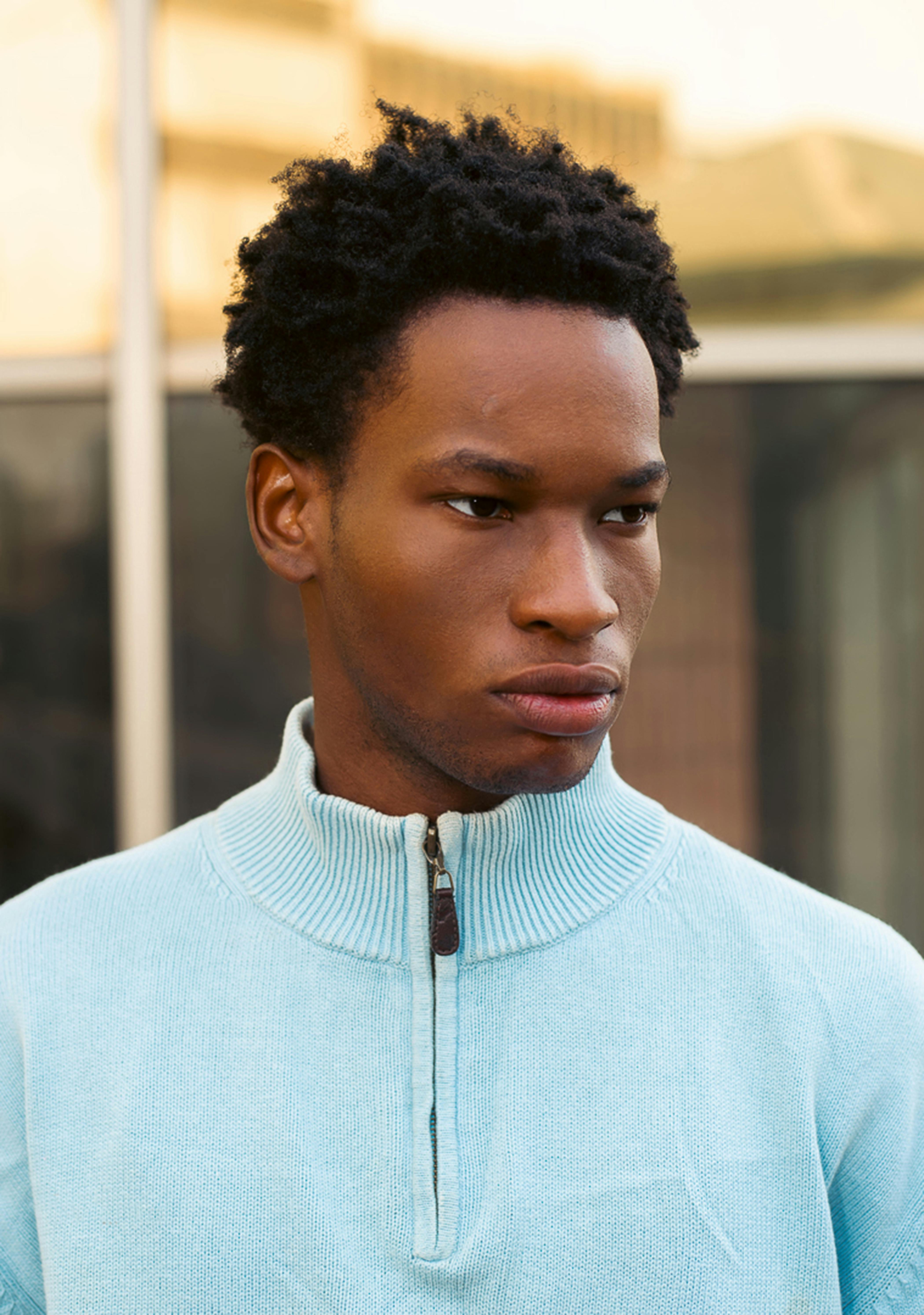 Portrait of a young man in a light blue sweater with a neutral expression.