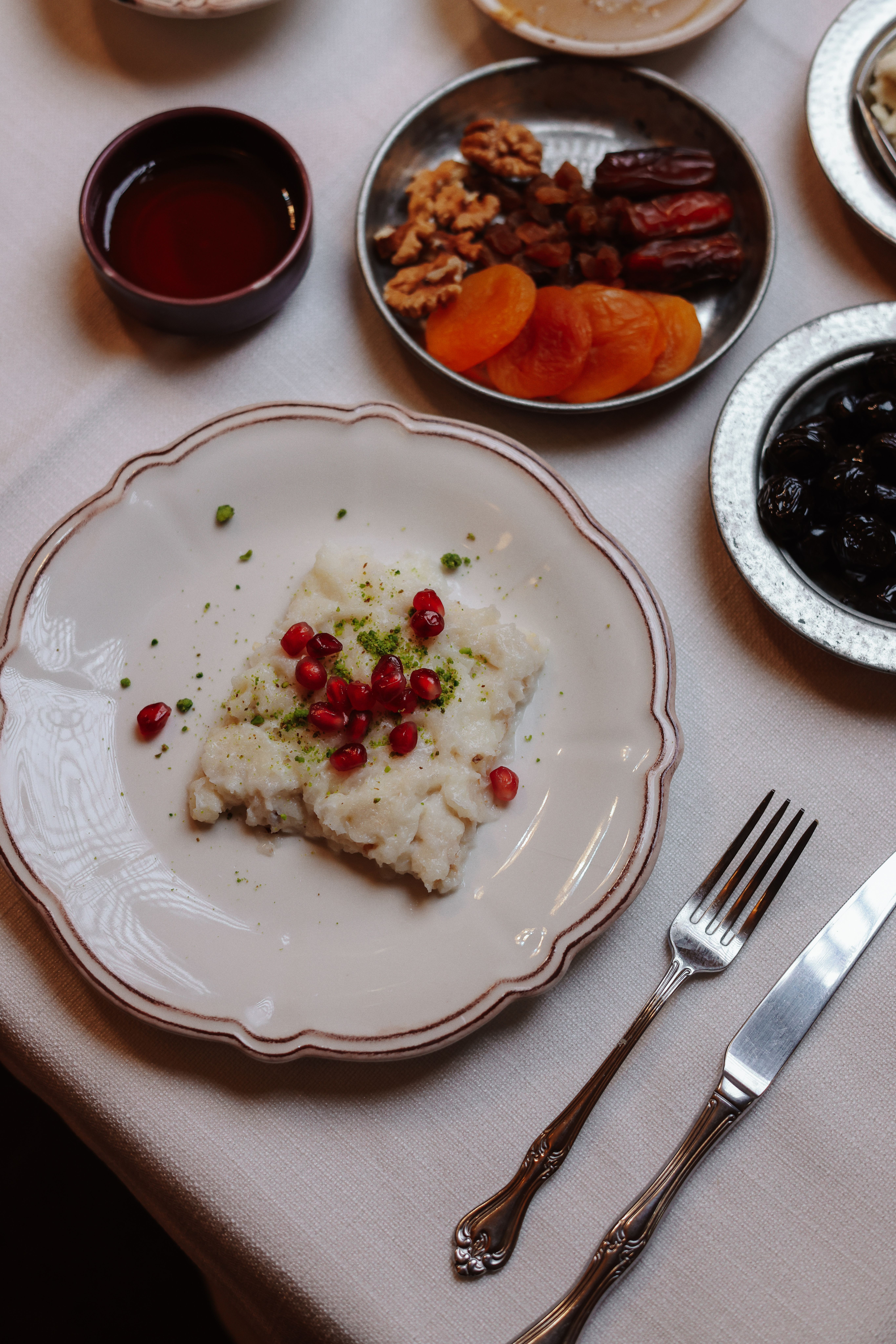 A beautifully arranged Ramadan iftar table featuring sweet treats, nuts, and a dish garnished with pomegranate seeds.