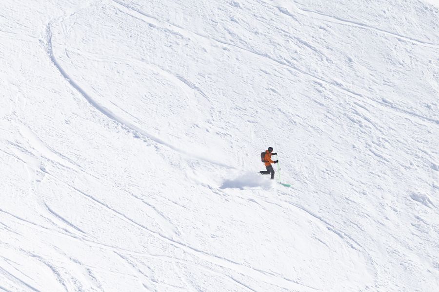 A lone skier carving a wide turn down an open snowfield — photo by Volker Meyer on Pexels