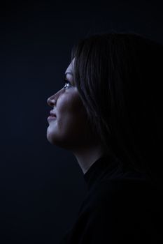 Side profile of a woman in dramatic low key lighting, emphasizing contours.. side, profile, woman