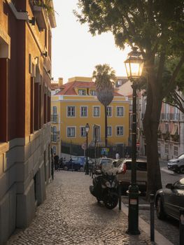 Cozy cobblestone street in Lisbon, Portugal, with warm sunset light and historic architecture.