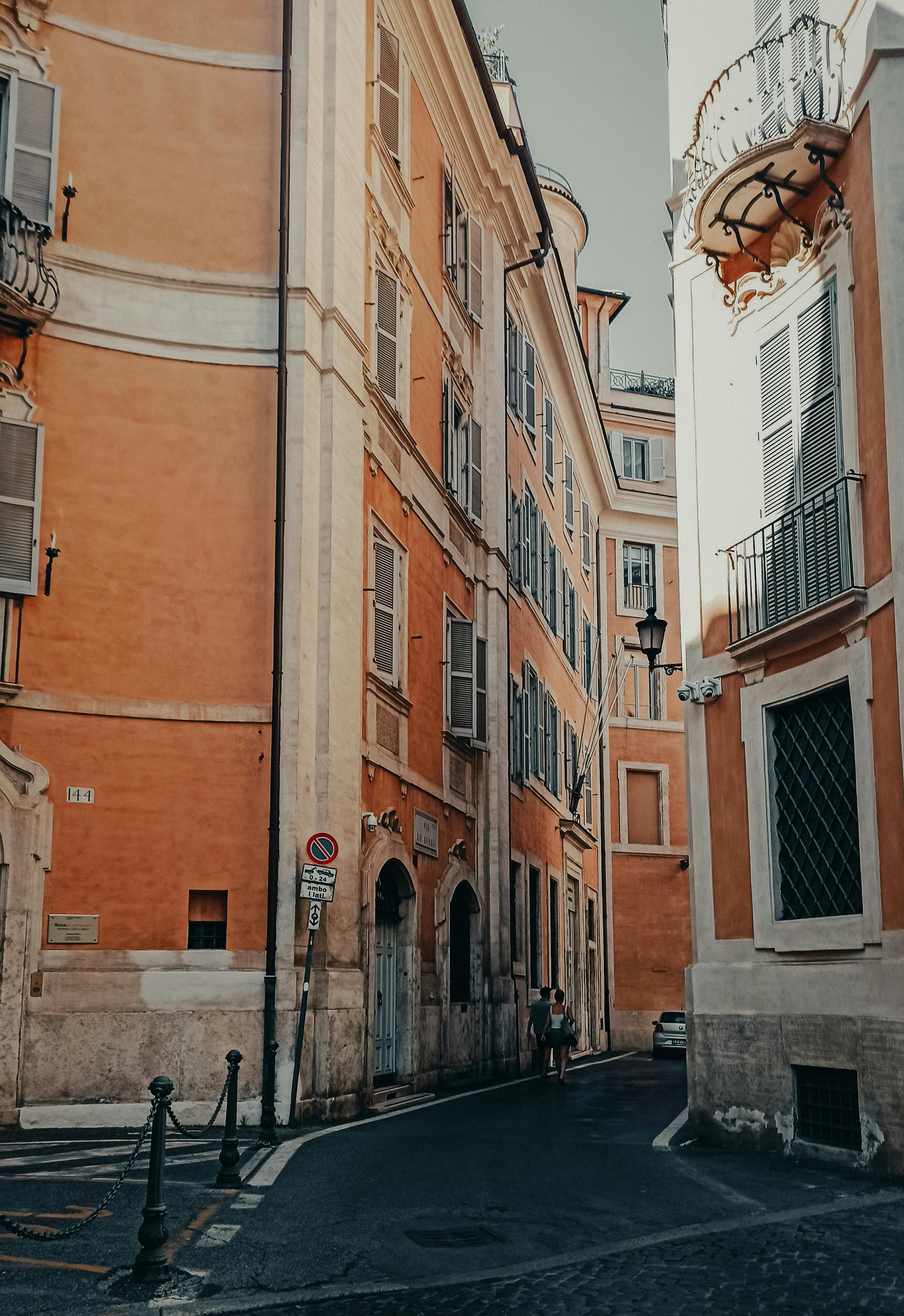 Charming cobblestone street in Rome lined with warm-toned historic buildings, traditional restaurants with outdoor seating, and a lively Mediterranean atmosphere in the Italian capital