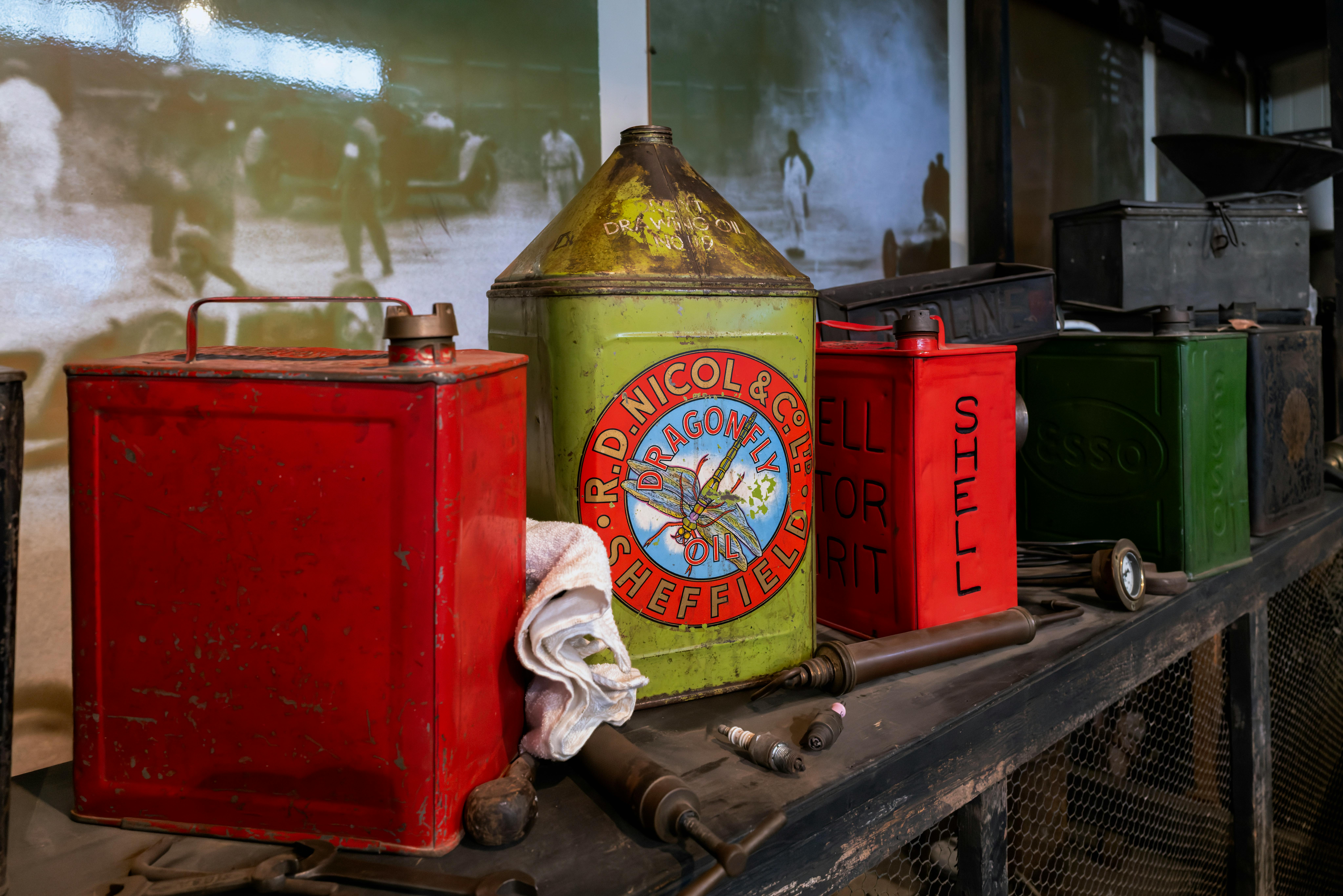 Безкоштовне Колекція старовинних каністр з-під олії на дерев'яній полиці в історичній гаражній виставці. стокове фото