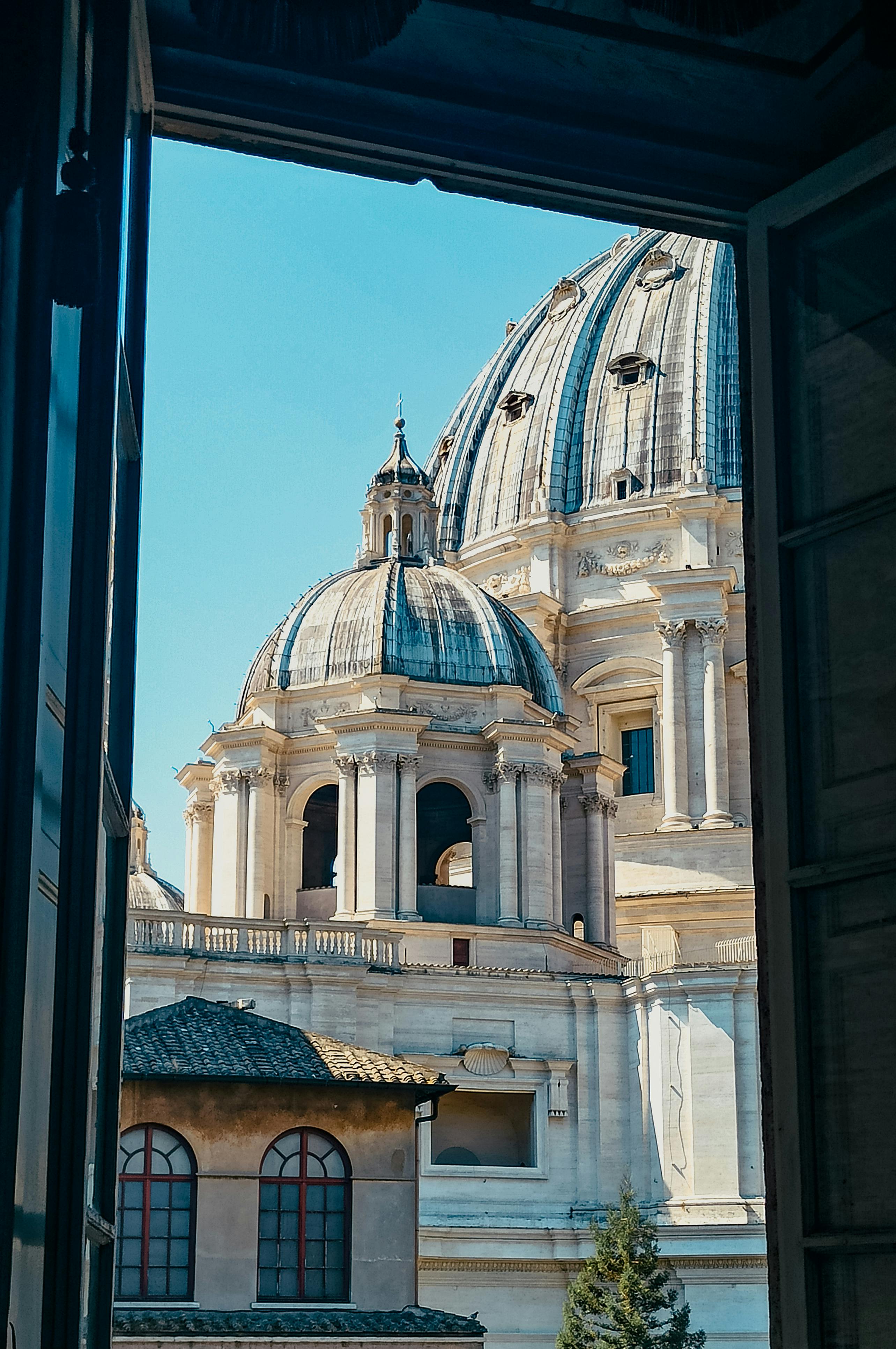 Безкоштовне Захопливий вид на купол базиліки Святого Петра з віконної рами у Ватикані, демонструючи приголомшливу архітектуру. стокове фото