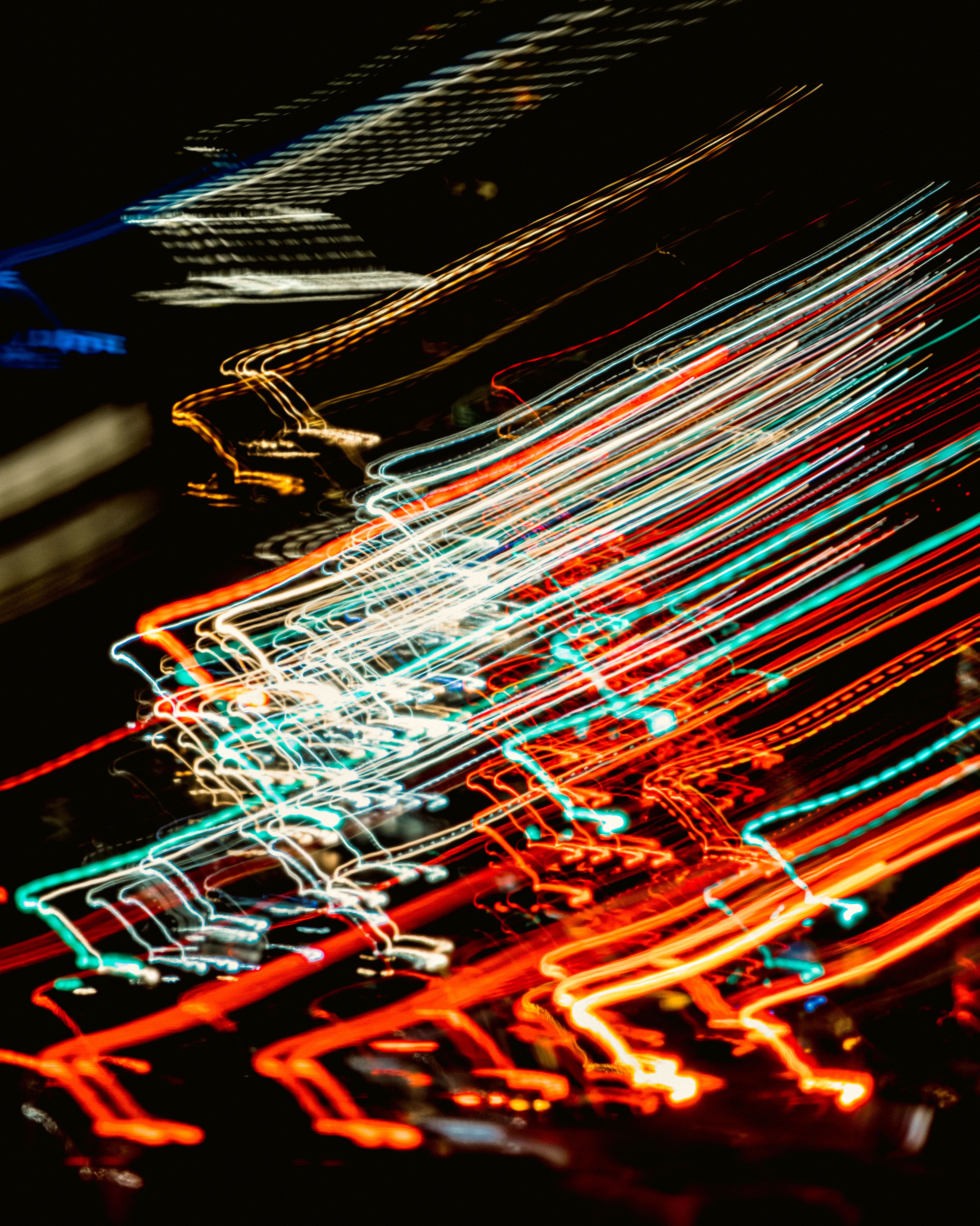 Blurred light trails create dynamic patterns in a night cityscape, capturing movement and energy.