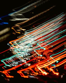 Blurred light trails create dynamic patterns in a night cityscape, capturing movement and energy.
