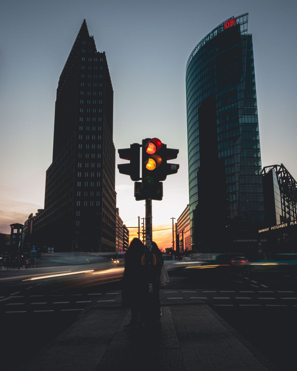 Urban night scene with skyscrapers and illuminated traffic light at dusk in Berlin.