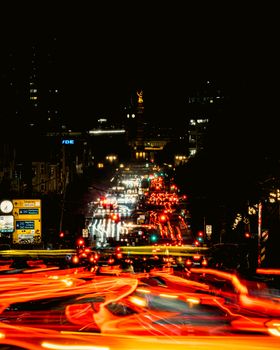 Long exposure of busy city streets at night capturing vibrant light trails and bustling traffic.