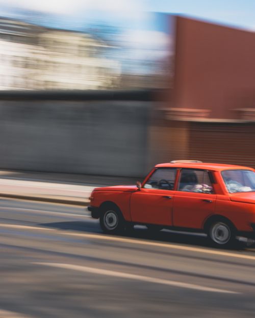 Free Red vintage car moving fast with blurred background on a city street. Stock Photo