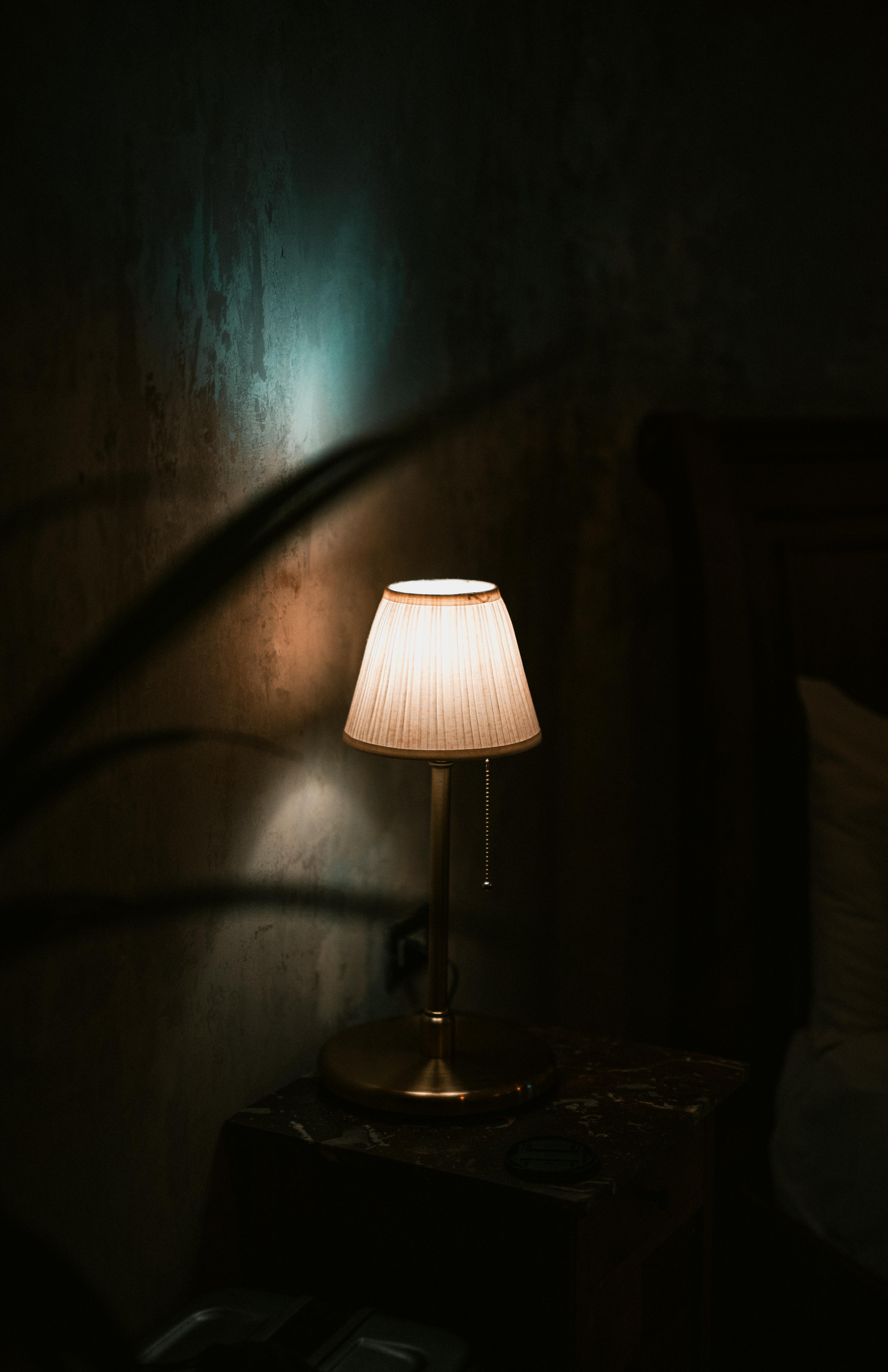 Zadarmo Teplá, jemne osvetlená stolová lampa vrhá tiene v útulnej miestnosti a vytvára príjemnú a intímnu atmosféru. Fotka z fotobanky