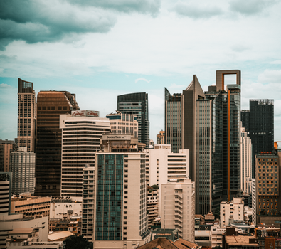Dramatic view of Bangkok's skyline showcasing modern skyscrapers under a cloudy sky.