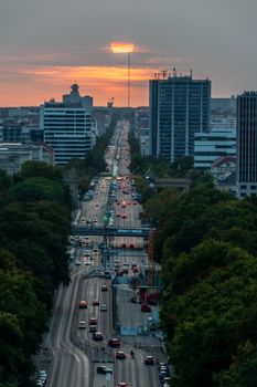 Aerial view of a busy urban street at sunset with high-rise buildings and vibrant colors.