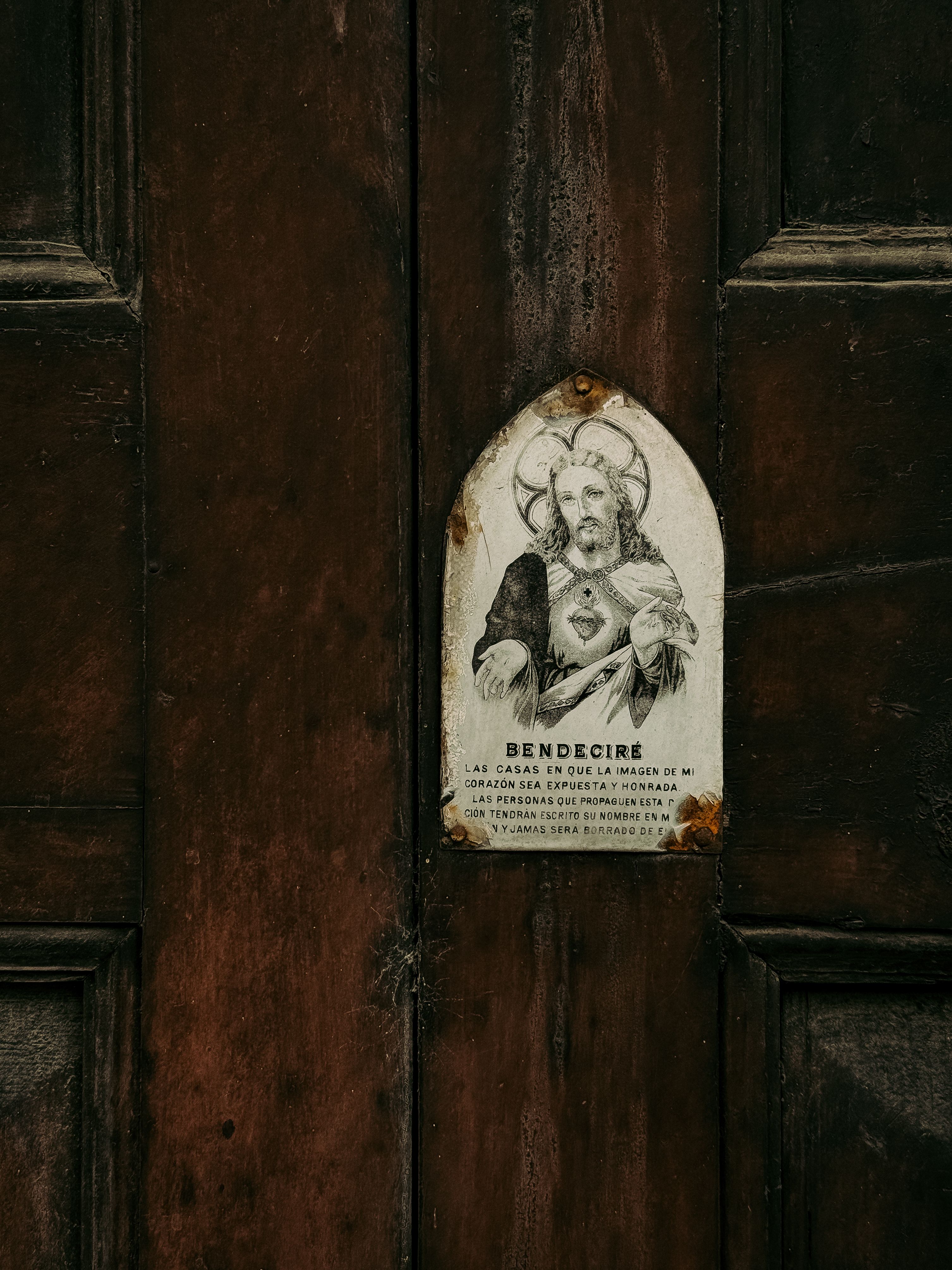 A vintage wooden door with a religious icon depicting Jesus, located in Ontinyent, Valencia.