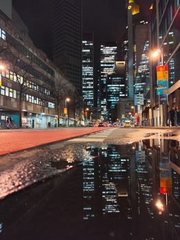 Vibrant nighttime city view of Frankfurt's skyline reflected in puddles.