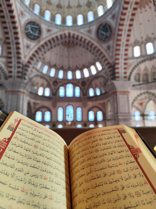 Free A Quran opened inside a mosque showcasing the beautiful architectural dome and arches. Stock Photo