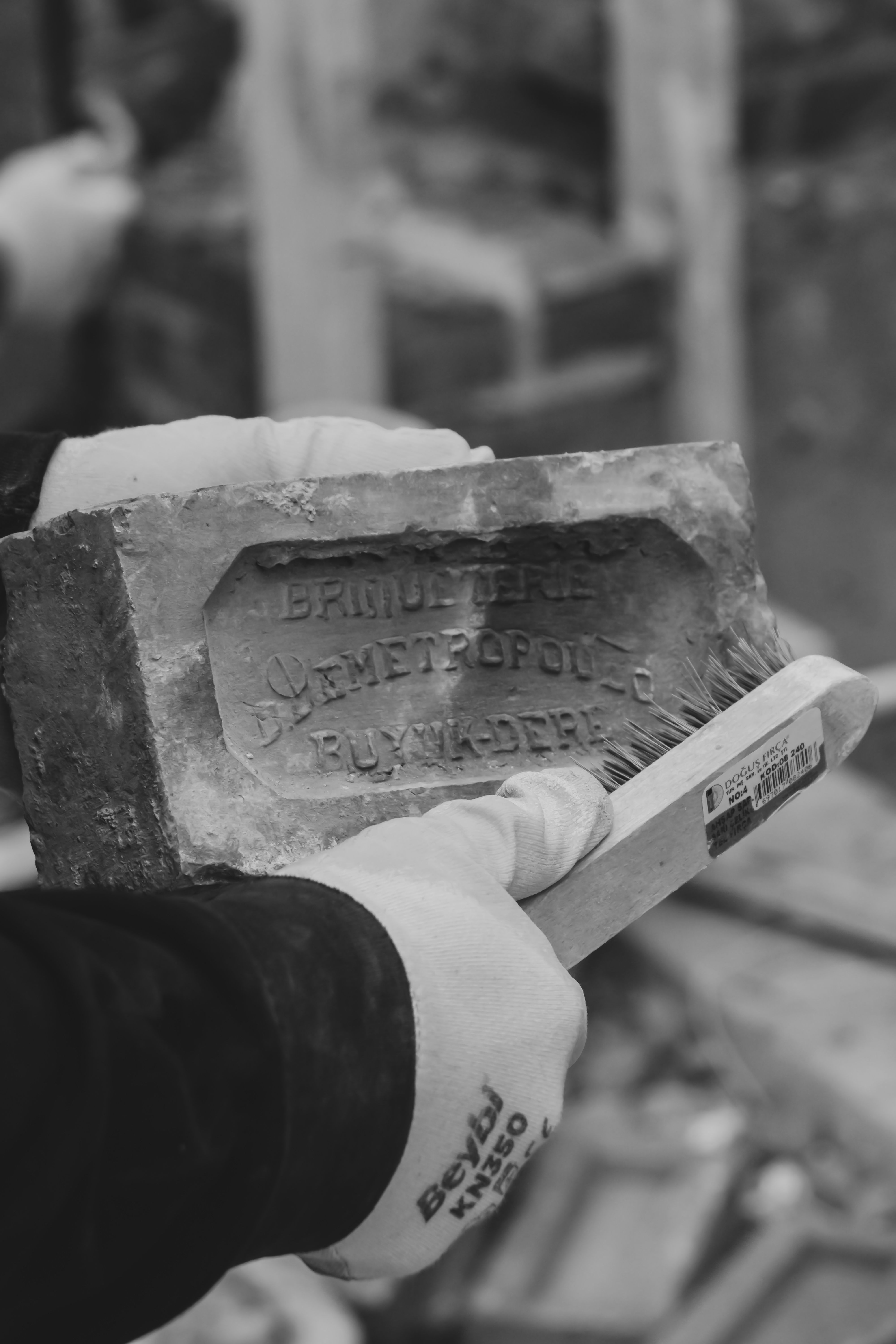 A close-up of hands cleaning a historical brick with engraved text. Timeless craftsmanship.