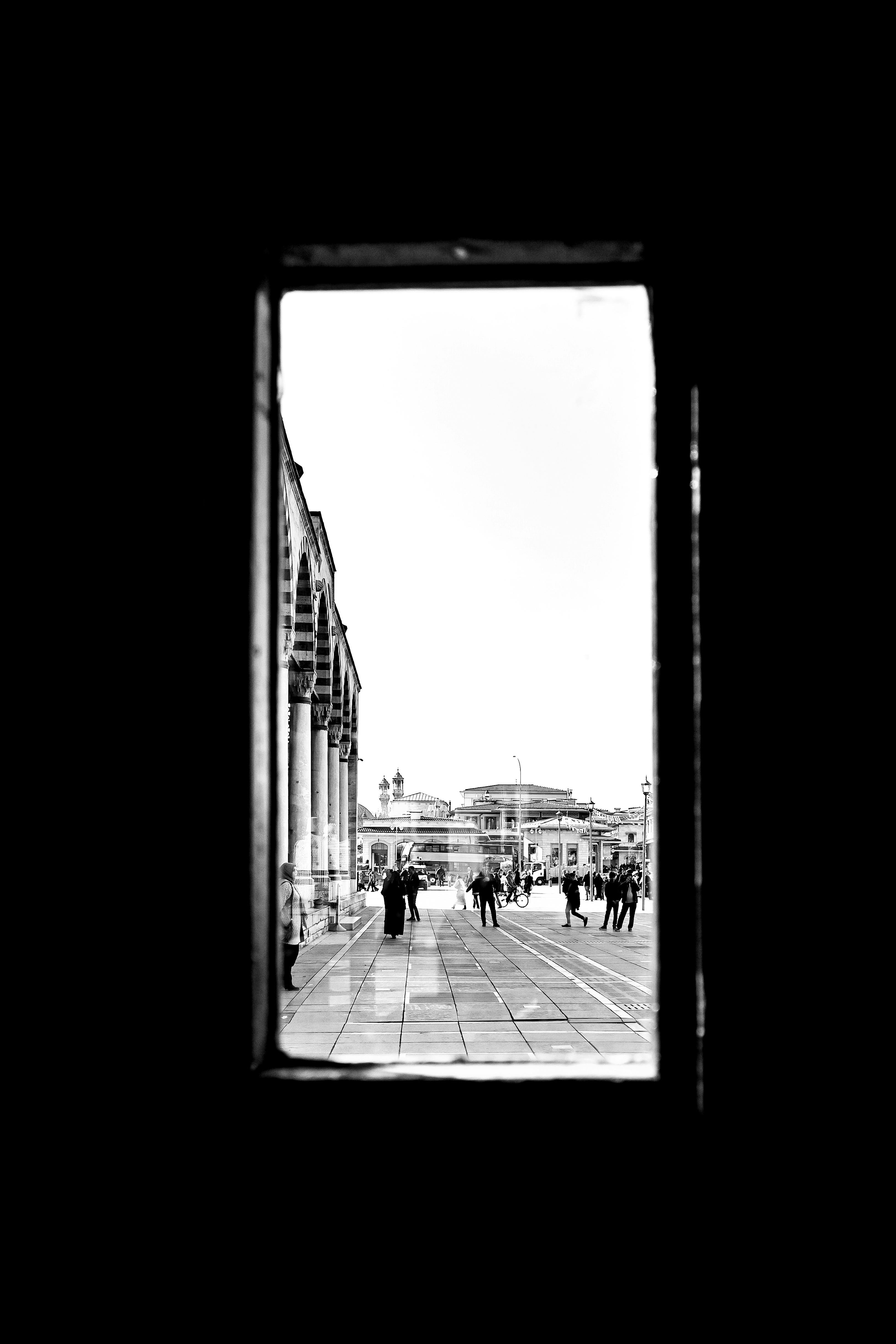 ingyenes Fekete-fehér utcai jelenet egy ablakból nézve, embereket és építészetet örökítve meg. Stockfotó