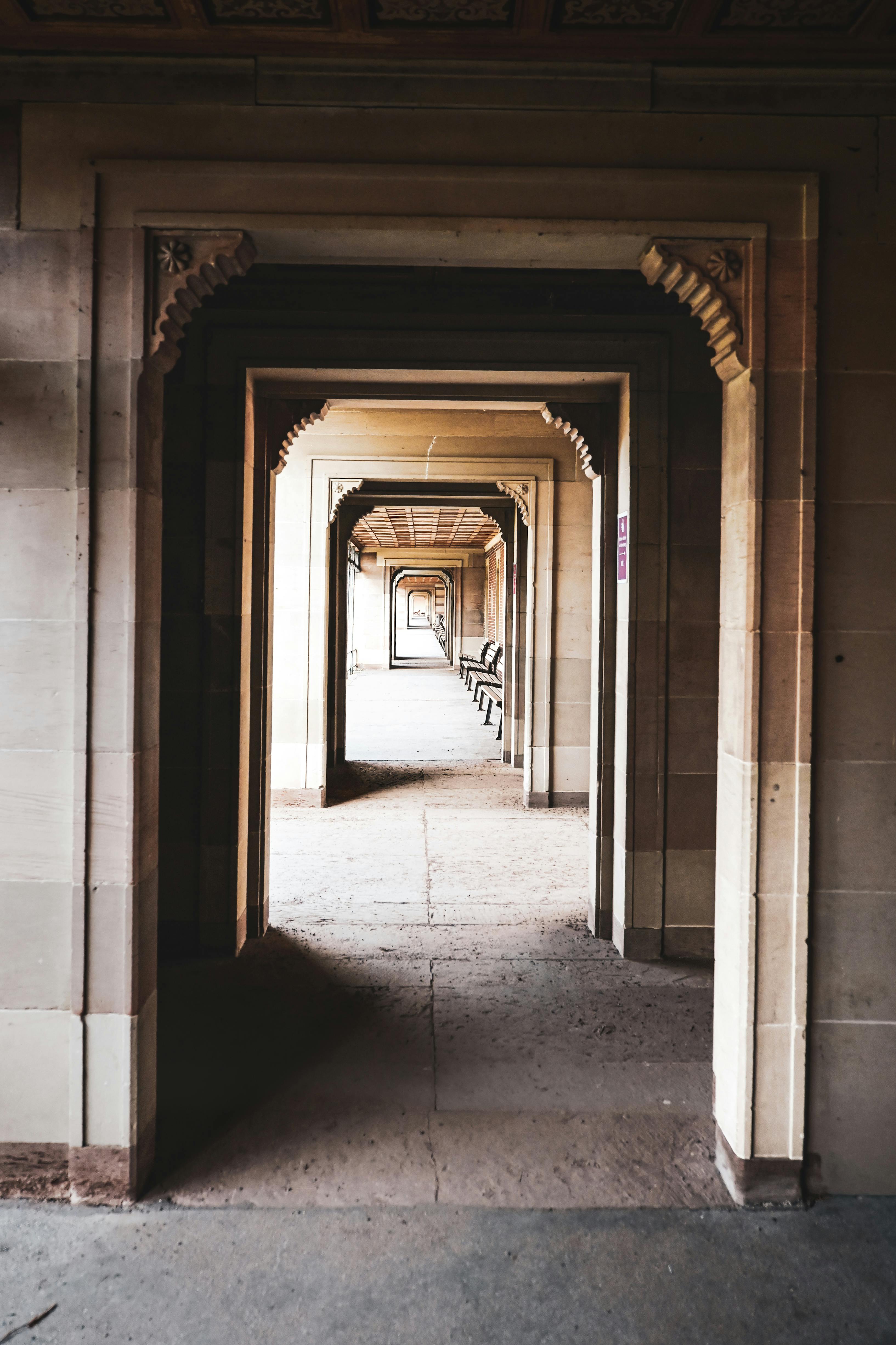 Gratuit Vue captivante à travers une série d'arcades en pierre symétriques dans un bâtiment historique, créant une perspective envoûtante. Photos