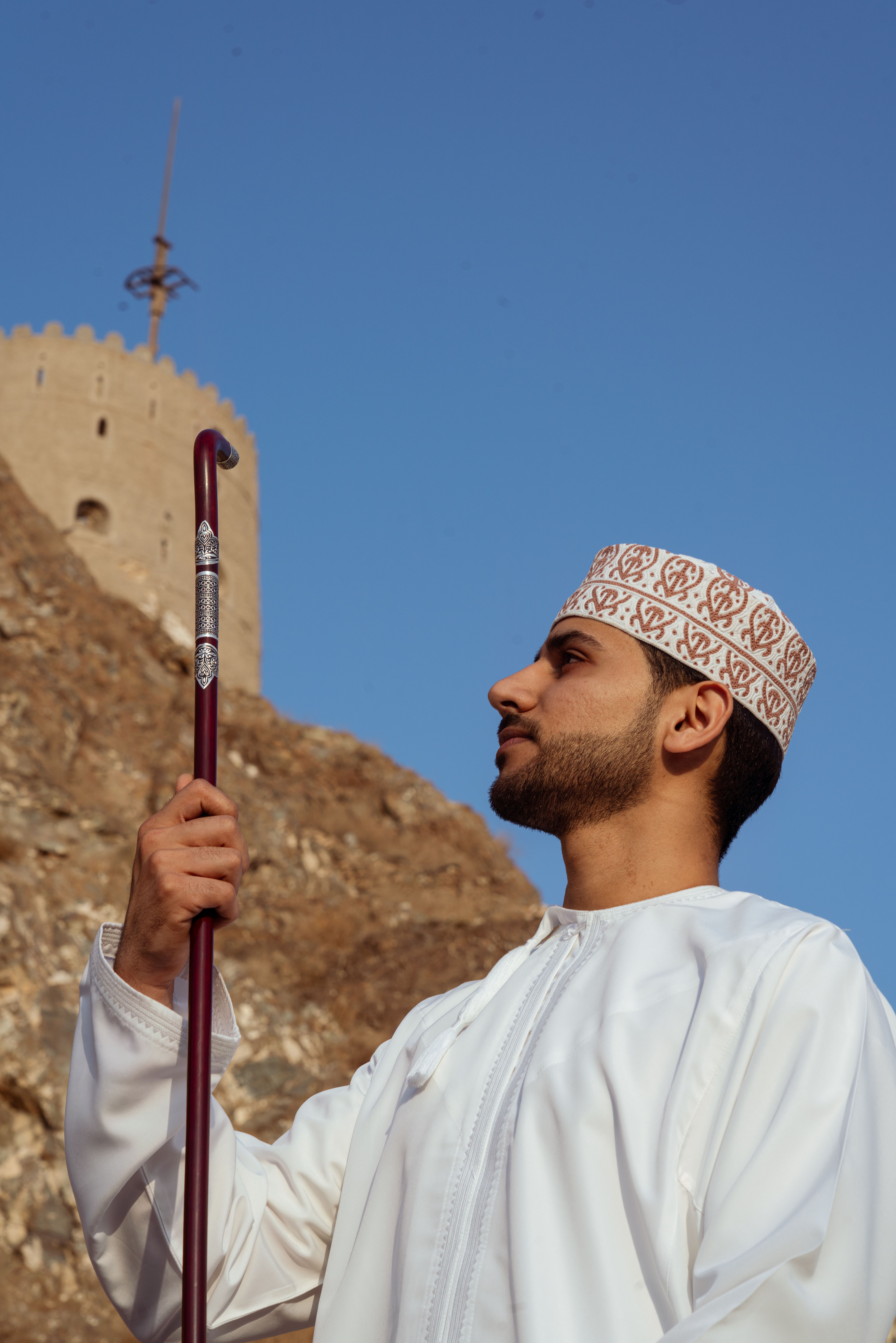 Omani Man in Traditional Attire by Muscat Fort · Free Stock Photo