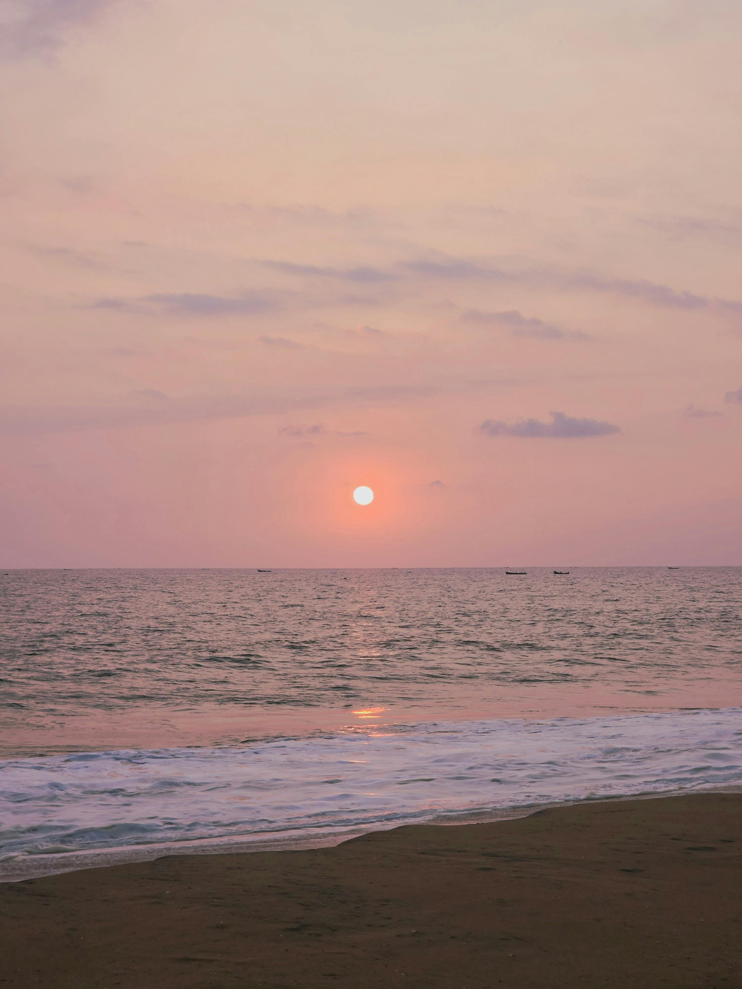 Безкоштовне Ніжний захід сонця над океаном з рожевим небом, що викликає спокой та умиротворення. стокове фото