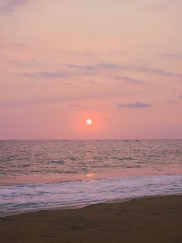 A gentle sunset over the ocean with a pink-hued sky, evoking peace and tranquility.