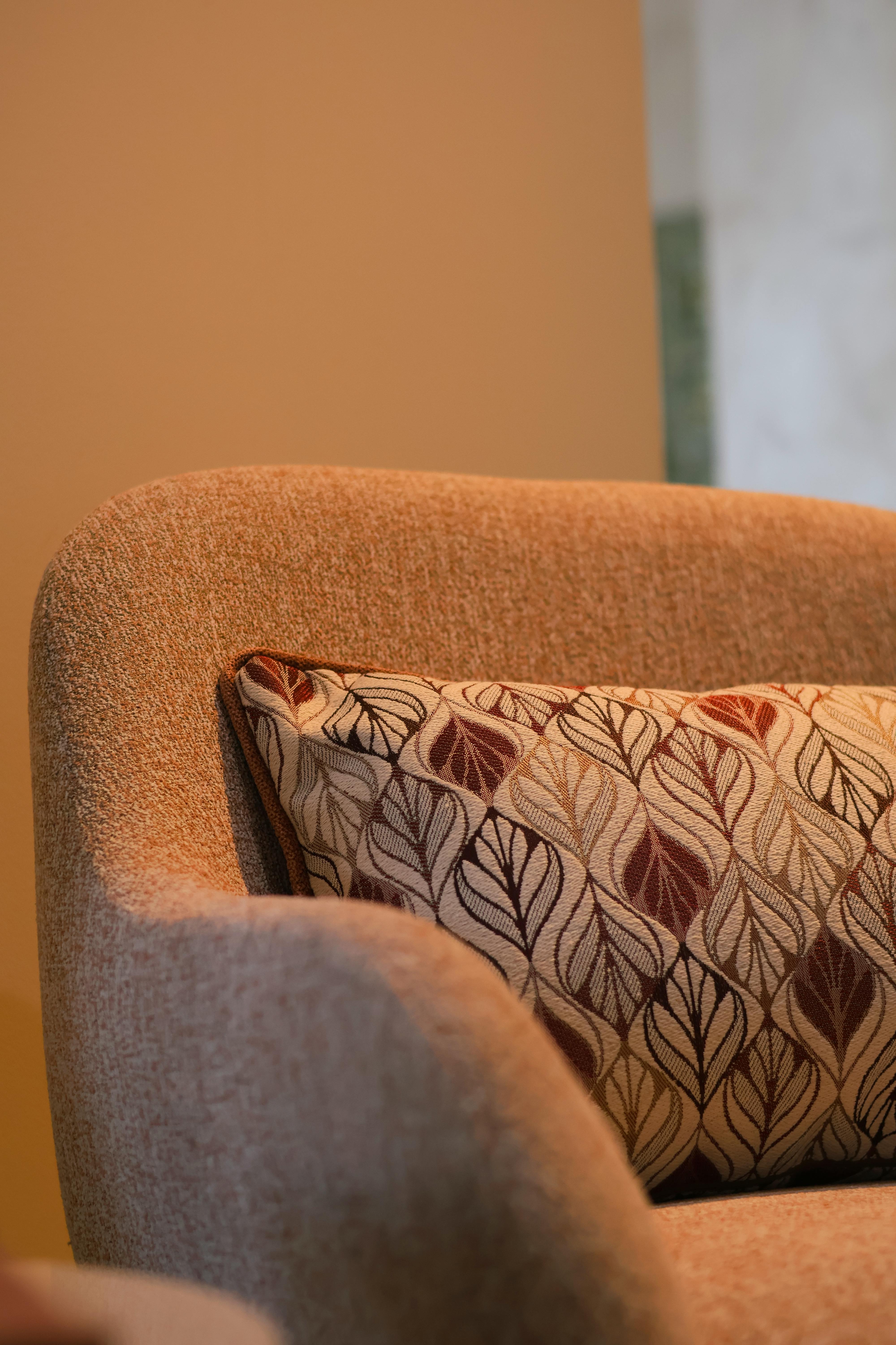 Zadarmo Štýlové kreslo so vzorovaným vankúšom v teplom interiéri, ideálne do bytu. Fotka z fotobanky