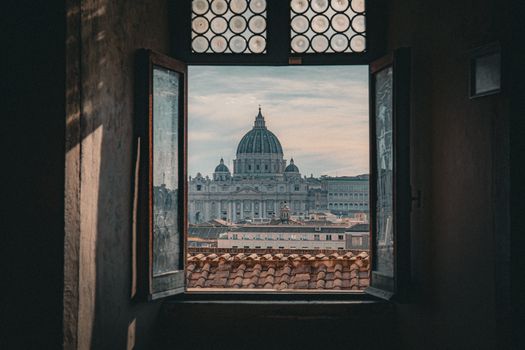 View of St. Peter's Basilica from an open window in Rome, Italy, capturing its iconic architecture.