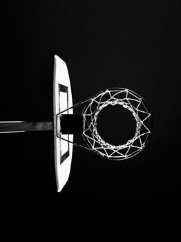 Abstract black and white photo of a basketball hoop from below, highlighting geometric elegance.