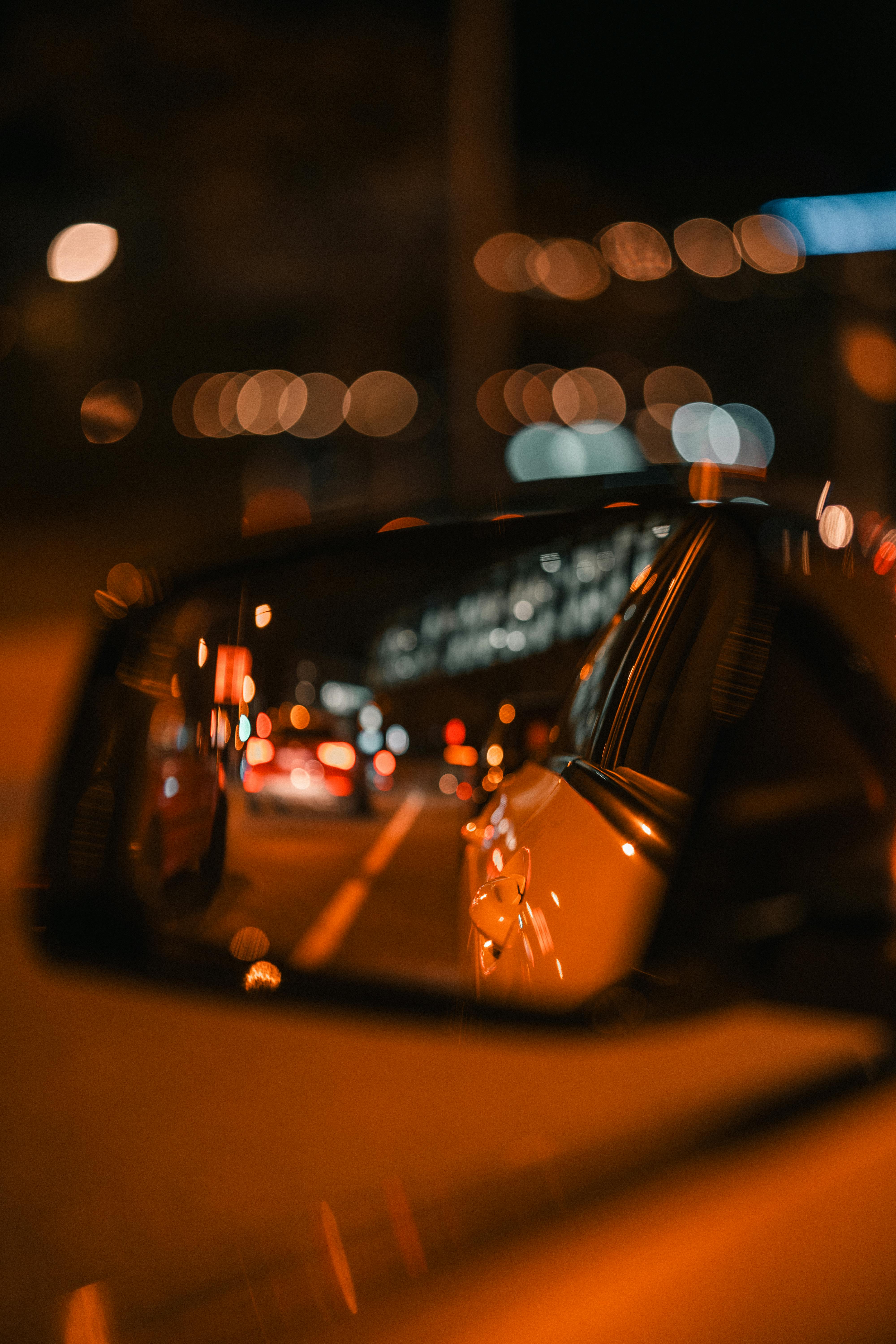 ingyenes Művészi megörökítés egy autó oldalsó visszapillantó tükörében tükröződő városi fényekről éjszaka. Stockfotó