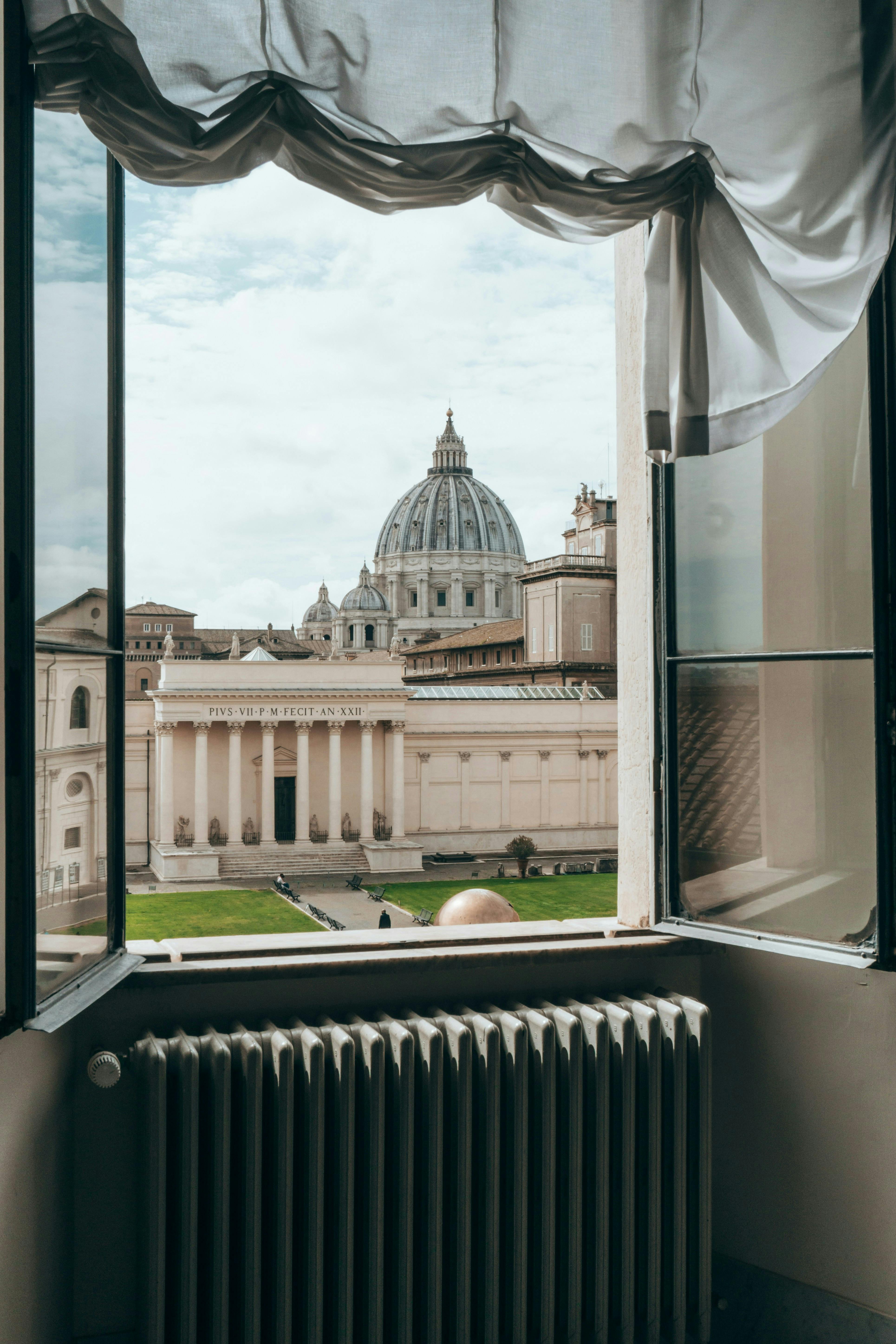 Bezpłatne Widok na Bazylikę św. Piotra z okna, podkreślający jej architektoniczną wspaniałość. Zdjęcie z galerii