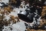 Captured from above, a car navigates a tree-lined street in Santiago, Chile, during fall.