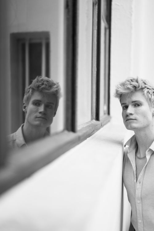 Free Monochrome portrait of a young man reflecting in the window indoors. Stock Photo