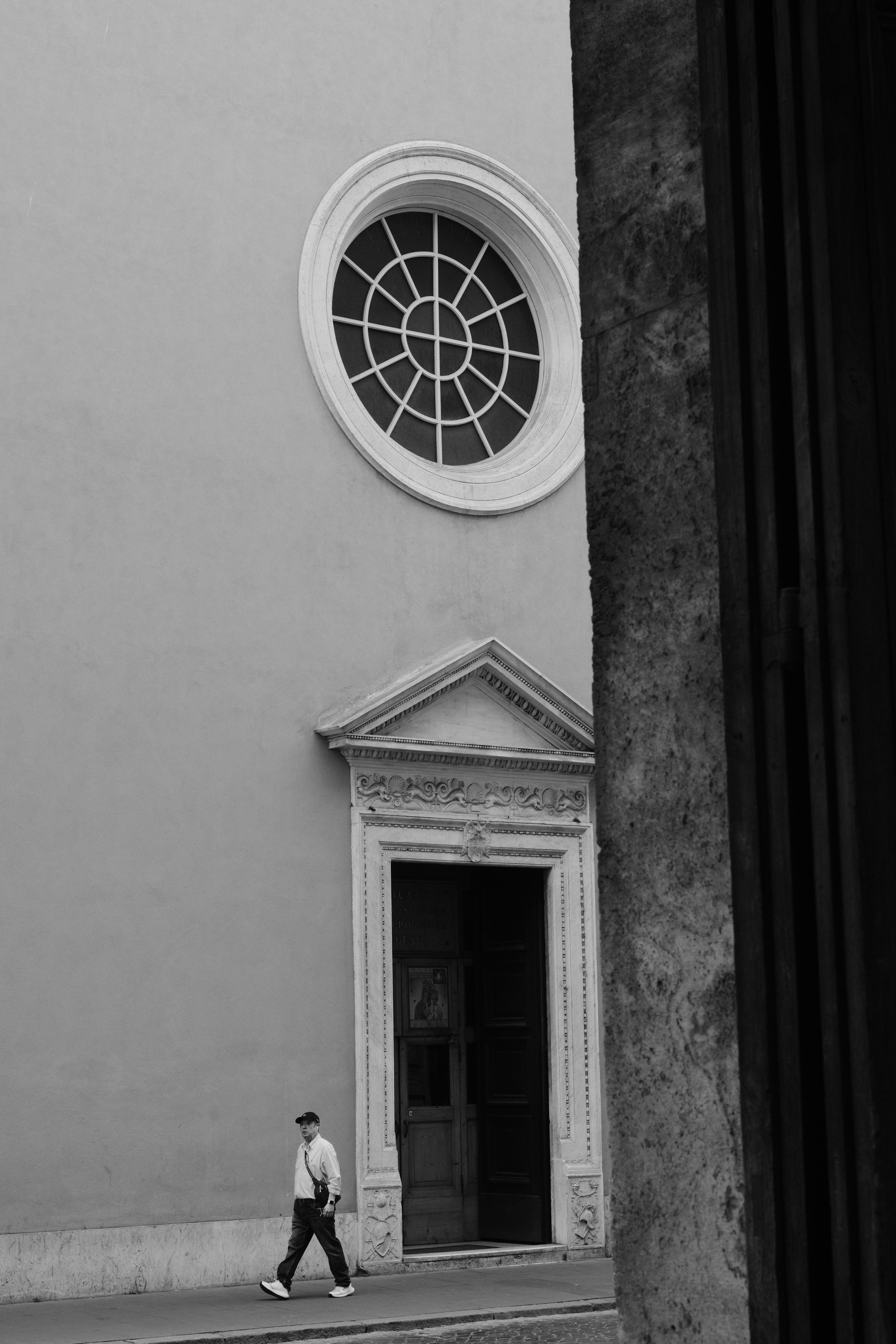 bezplatná Muž prochází kolem historické budovy s kruhovým oknem v Římě v Itálii. Základová fotografie