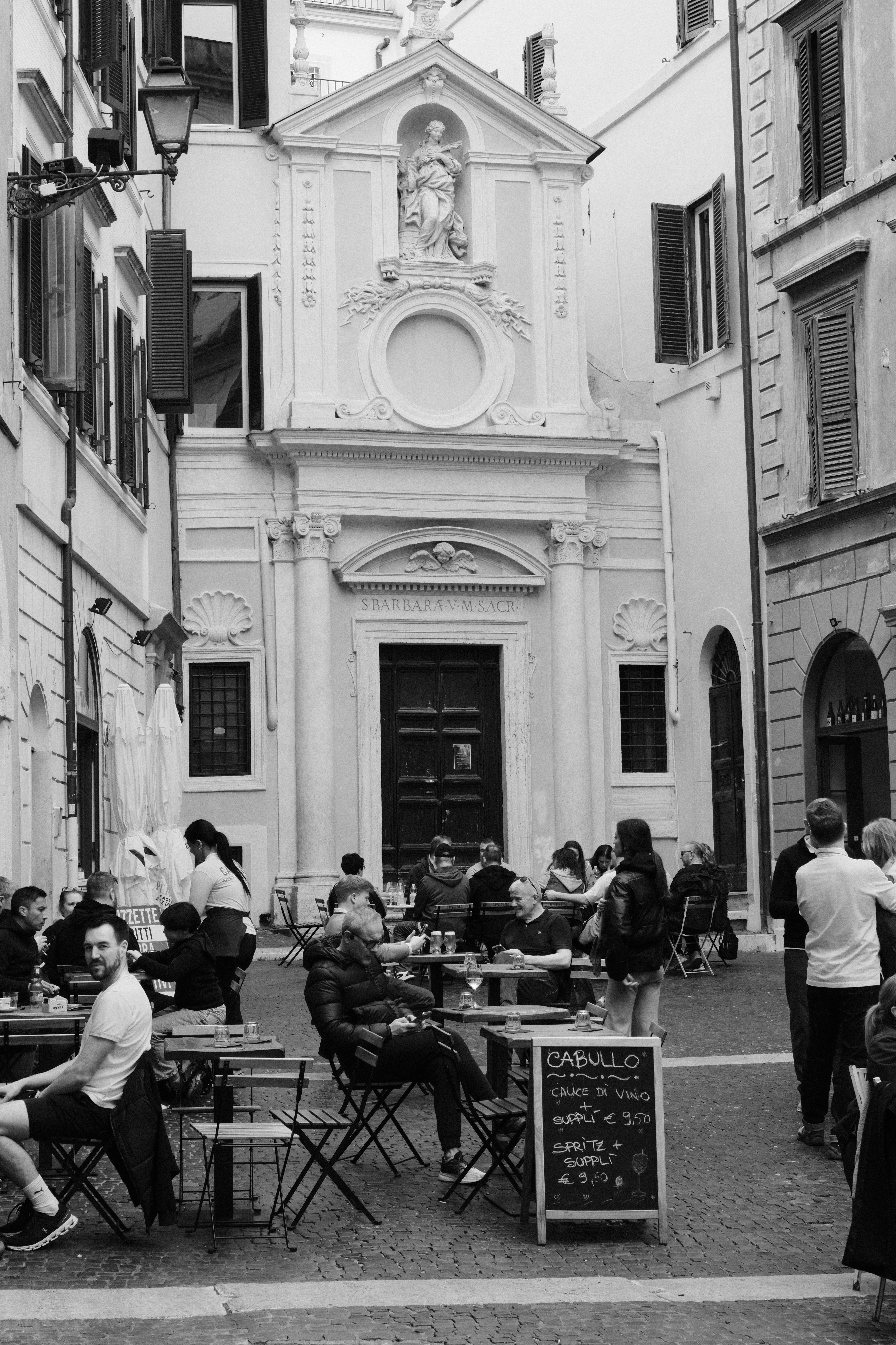 Lively street cafe scene in Rome, Italy with patrons enjoying outdoor dining near historic architecture.