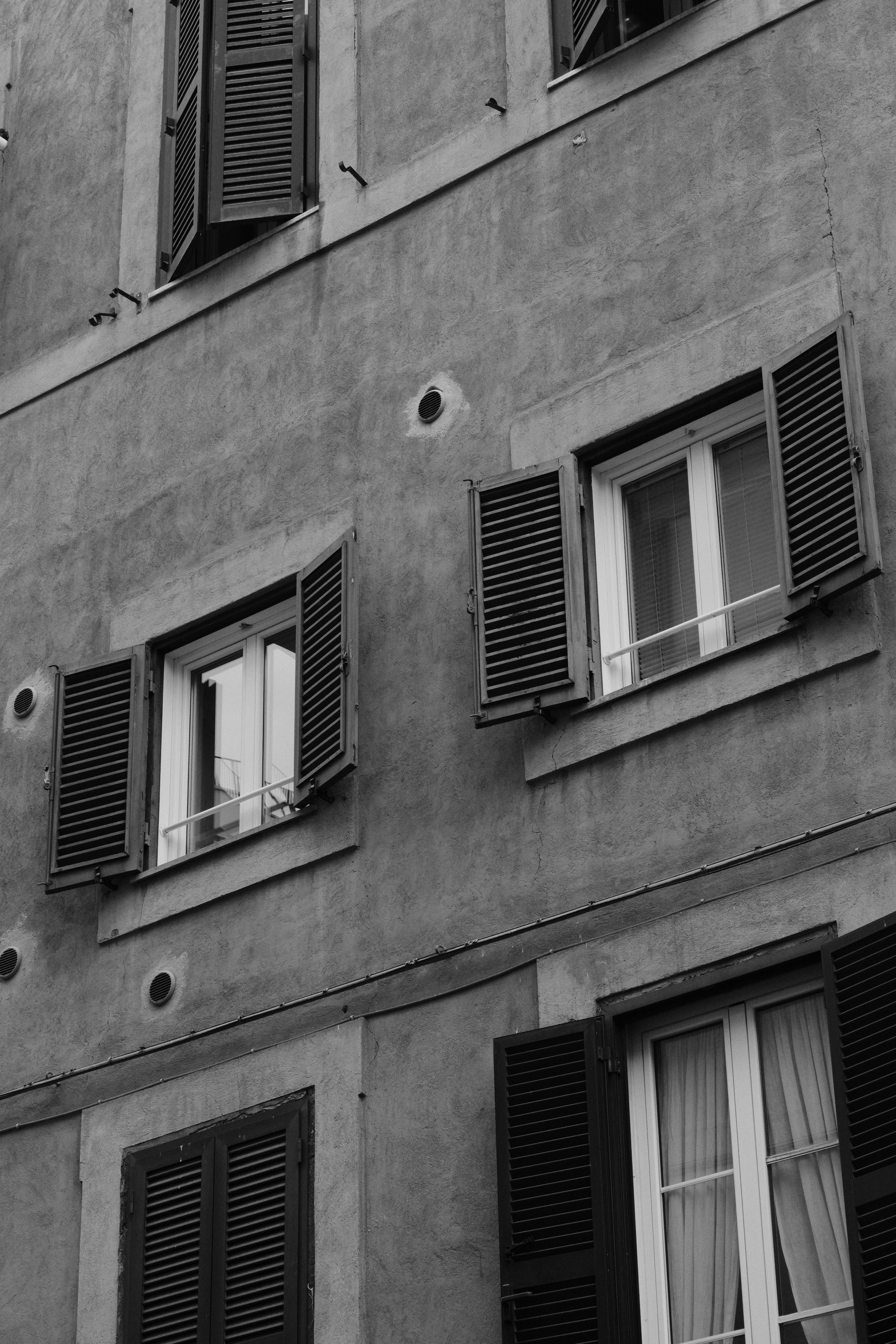 Zadarmo Čiernobiela fotografia starej fasády budovy s otvorenými okenicami v Ríme v Taliansku. Fotka z fotobanky