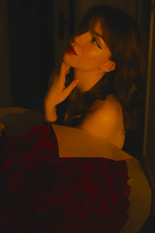 Free Portrait of a woman holding a bouquet of red roses with a soft light ambiance in Wrocław, Poland. Stock Photo