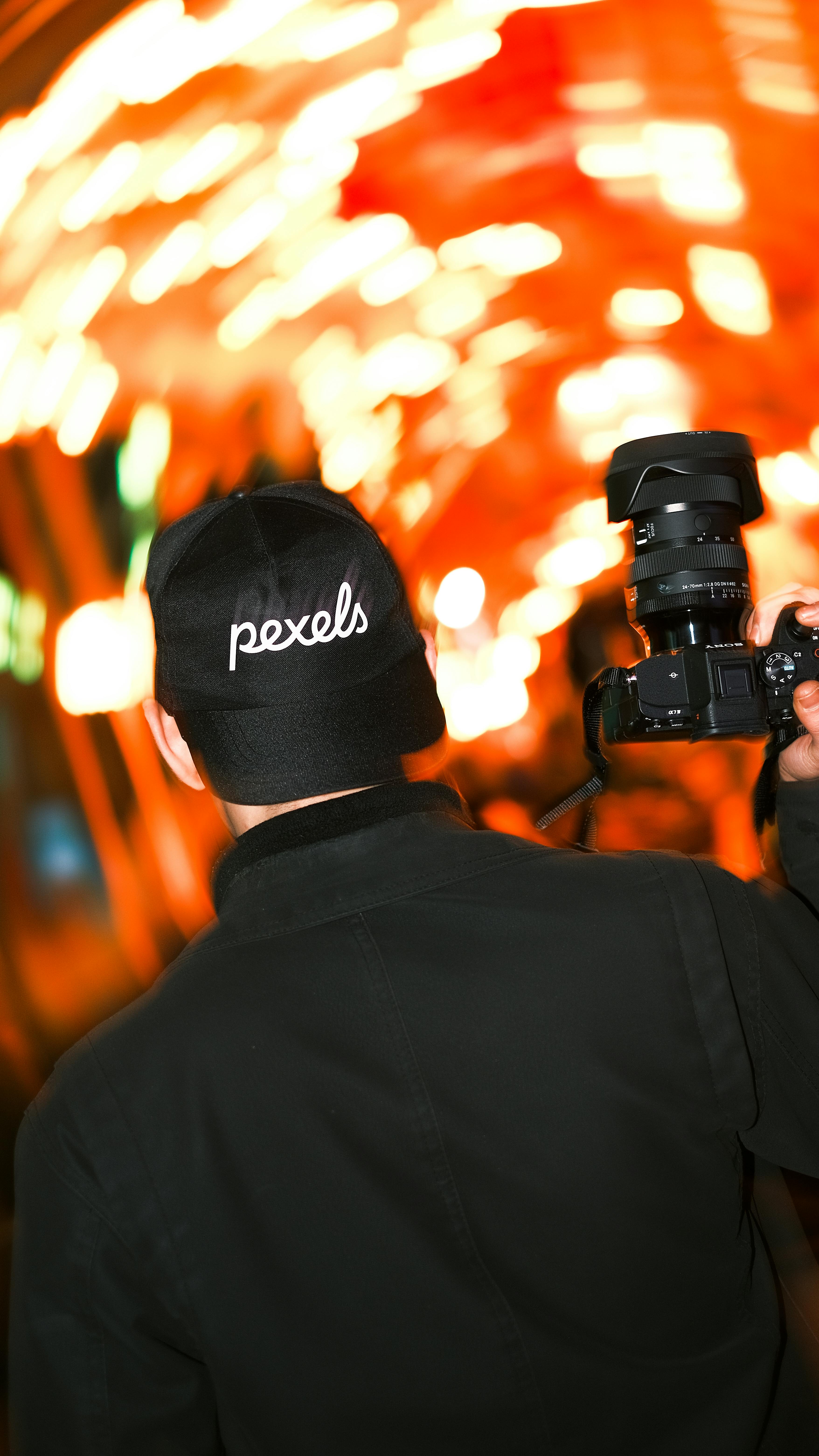 Miễn phí Một người đàn ông cầm máy ảnh ghi lại hình ảnh lung linh của ánh đèn thành phố về đêm, tạo hiệu ứng bùng nổ. Ảnh lưu trữ