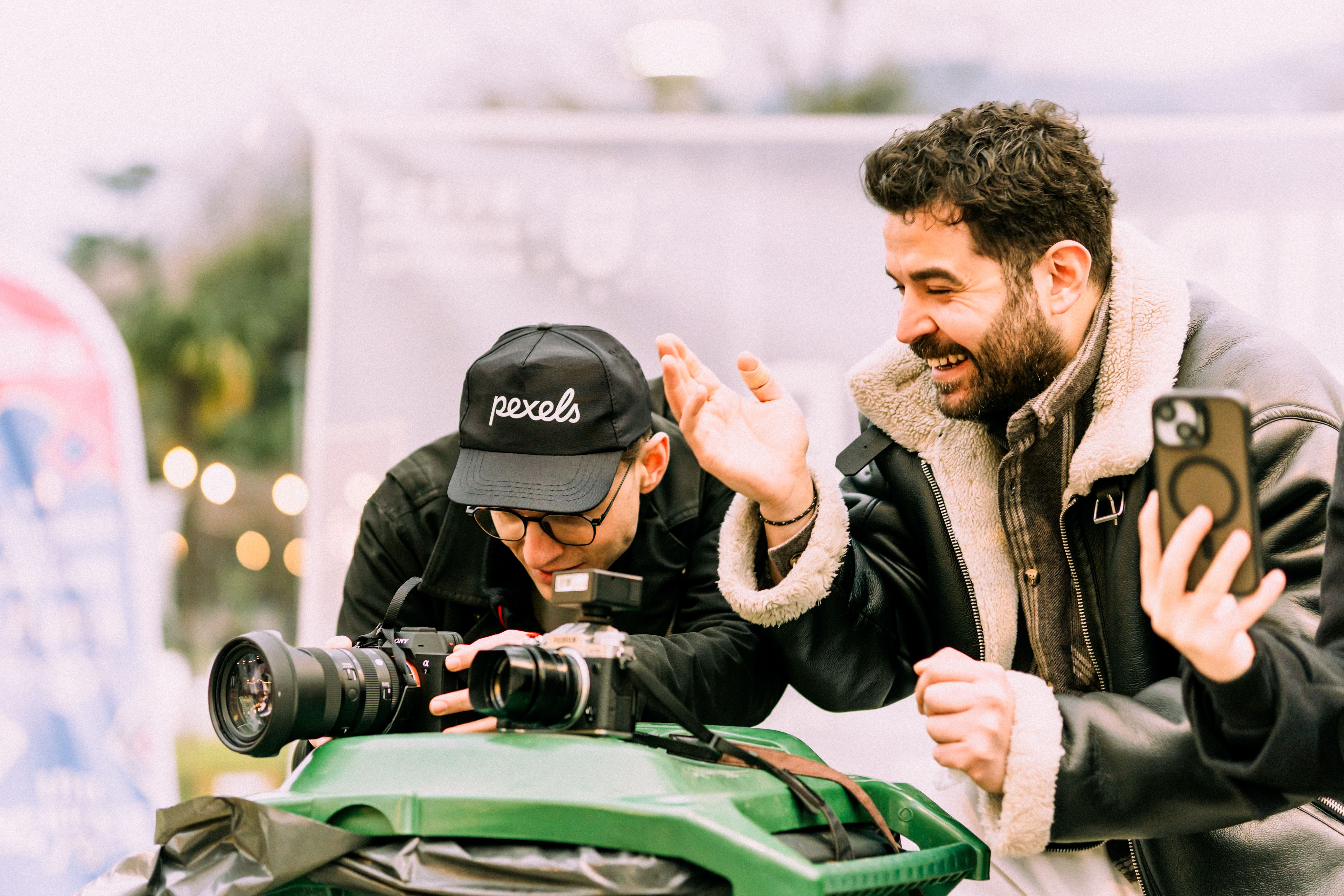 Two photographers creatively collaborate outdoors, enjoying the process of capturing the perfect shot.