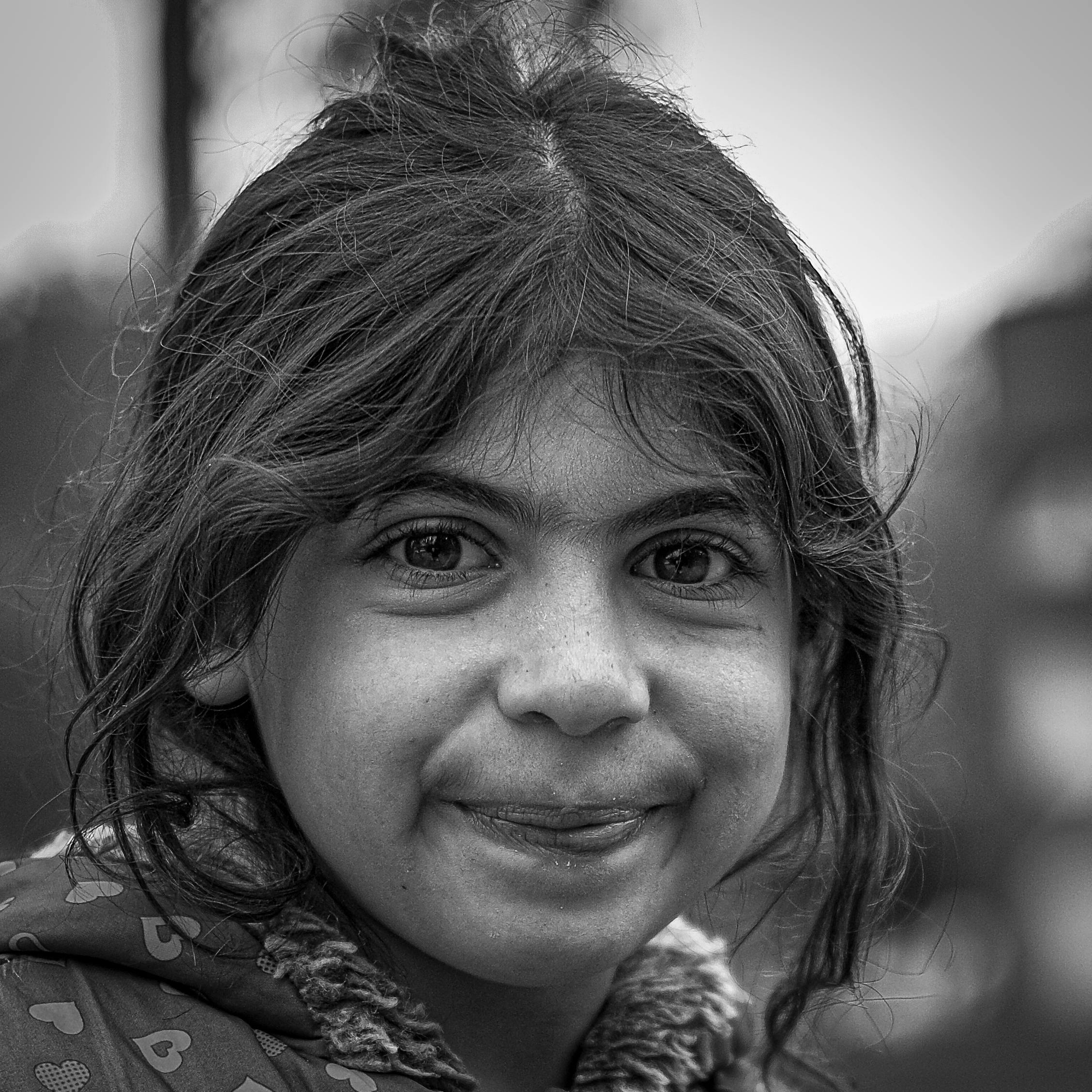 gratis Een betoverend zwart-witportret van een jong meisje dat buiten lachend poseert, waarbij onschuld en vreugde centraal staan. Stockfoto